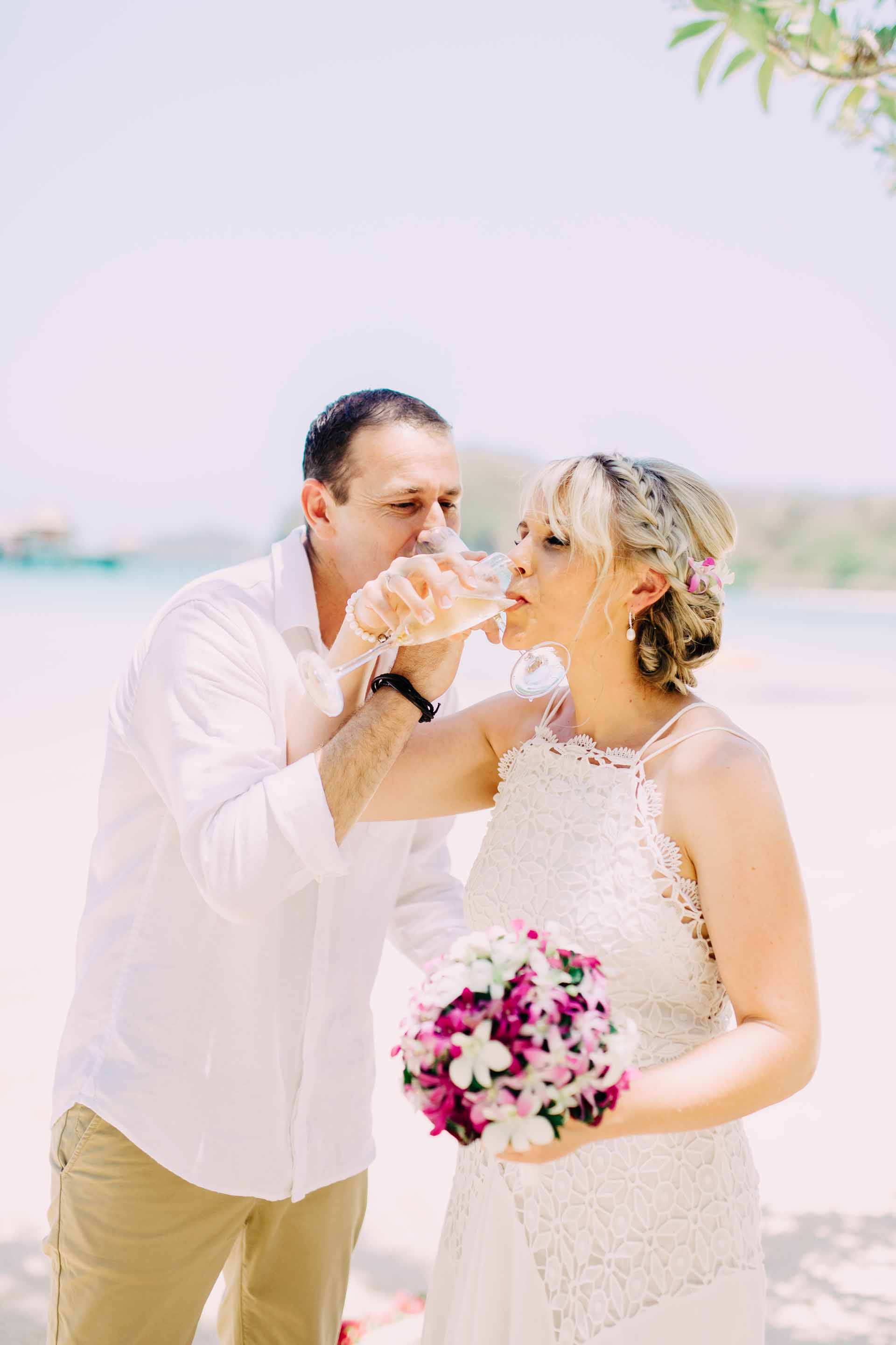 the couple entwine hands to drink their champagne