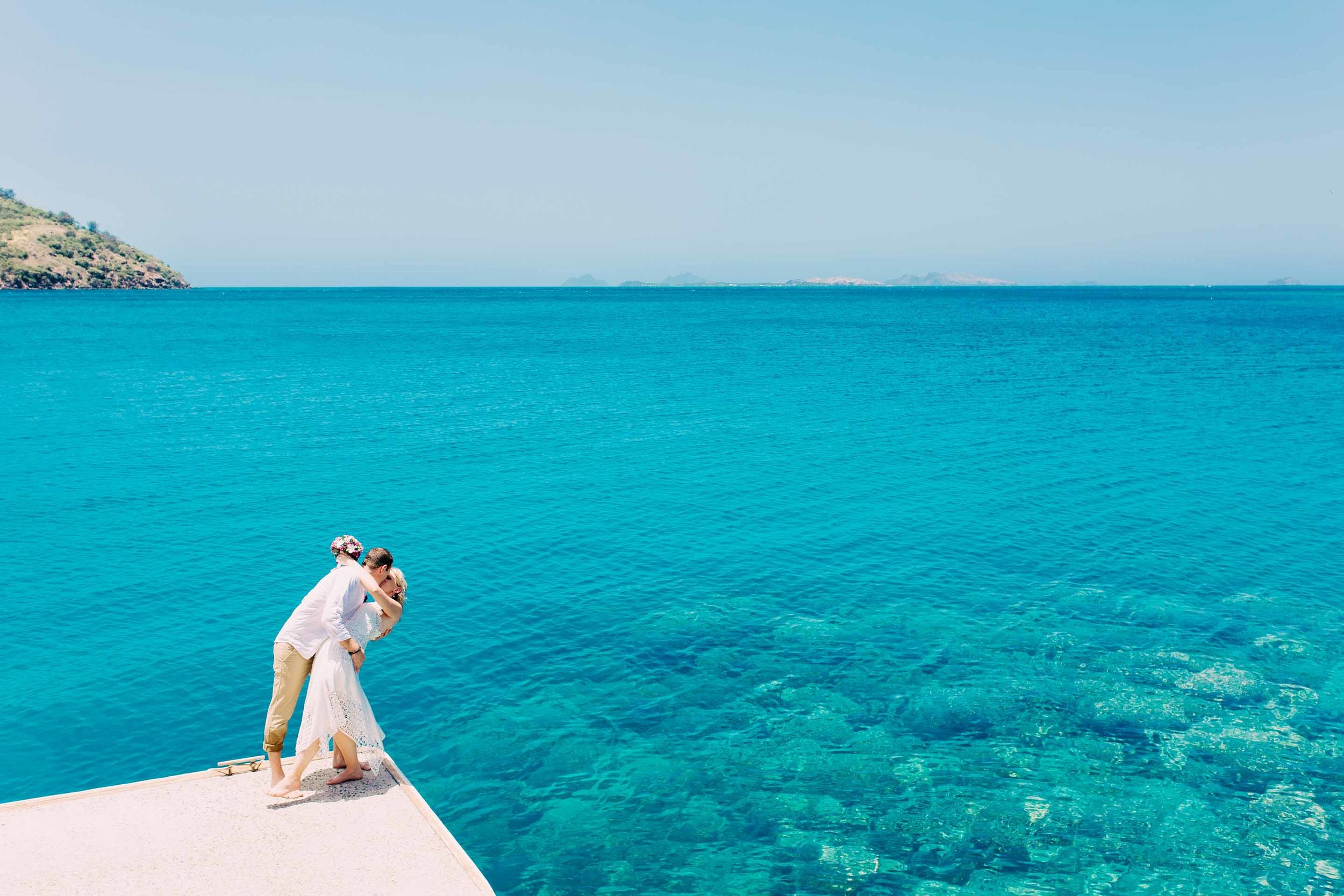 the couple dipping and kissing with the stunning blues and vibrant colours of the reef behind them