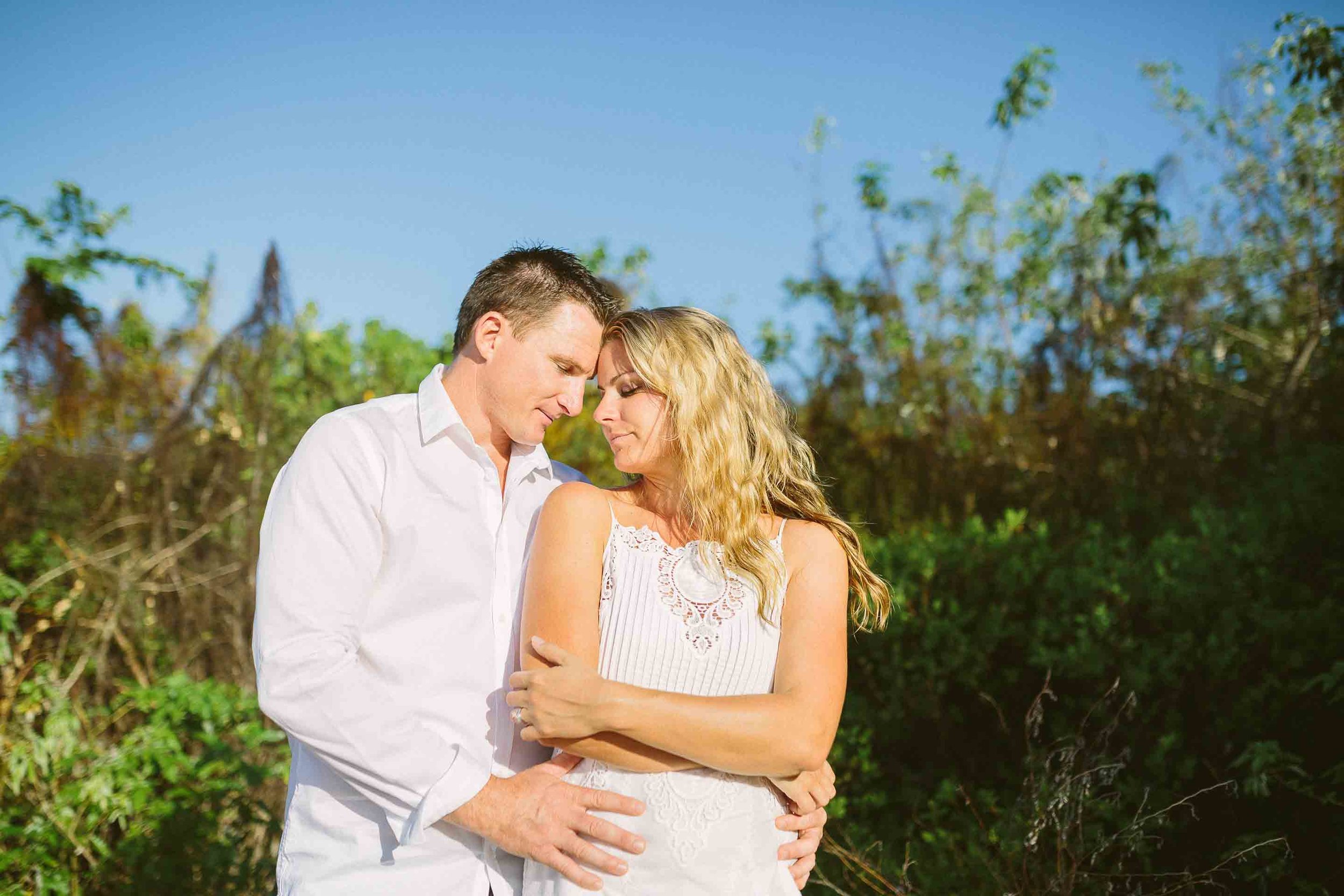 bride and groom touching each other in a field of tall grass