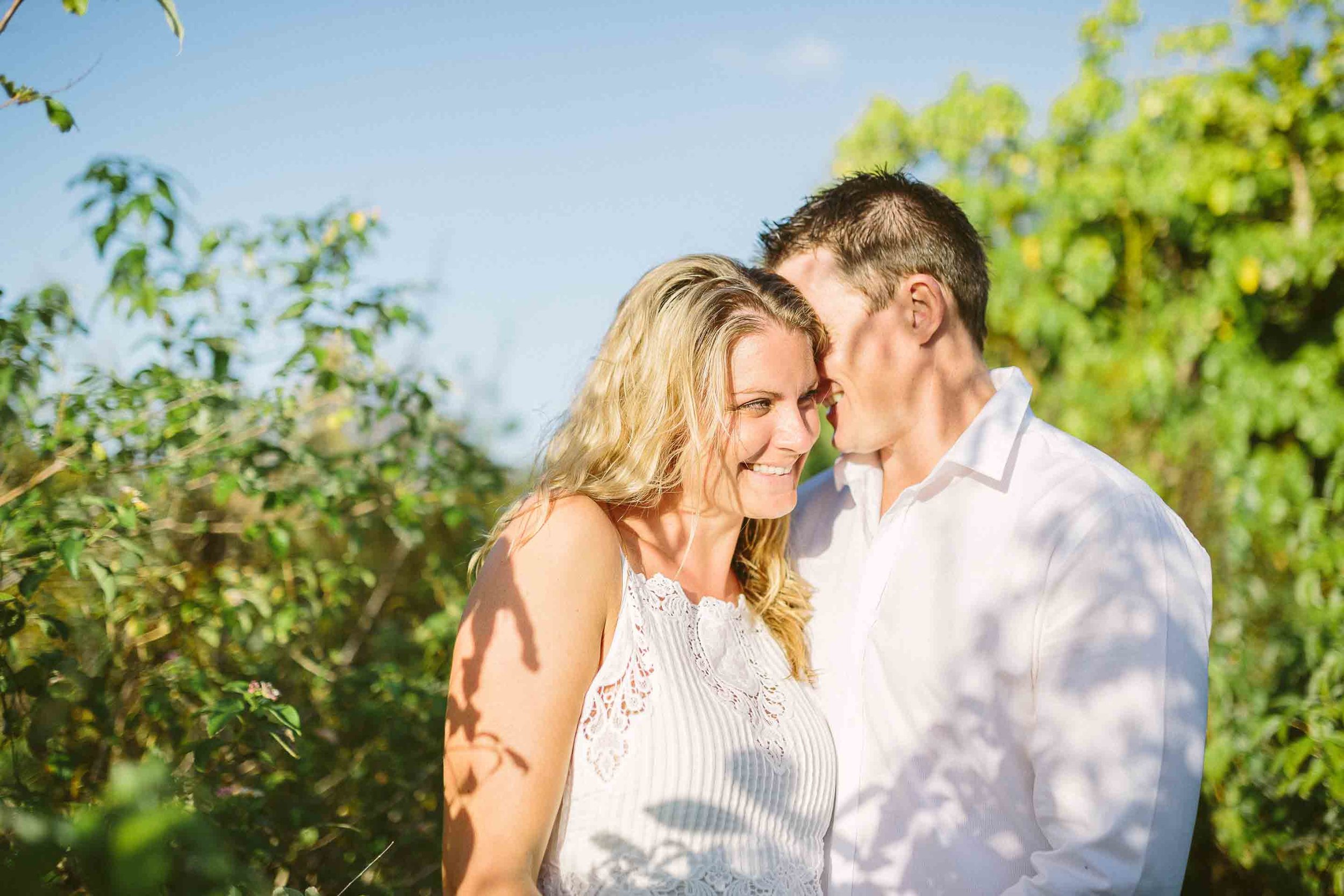 groom kissing bride on cheek in tall grass