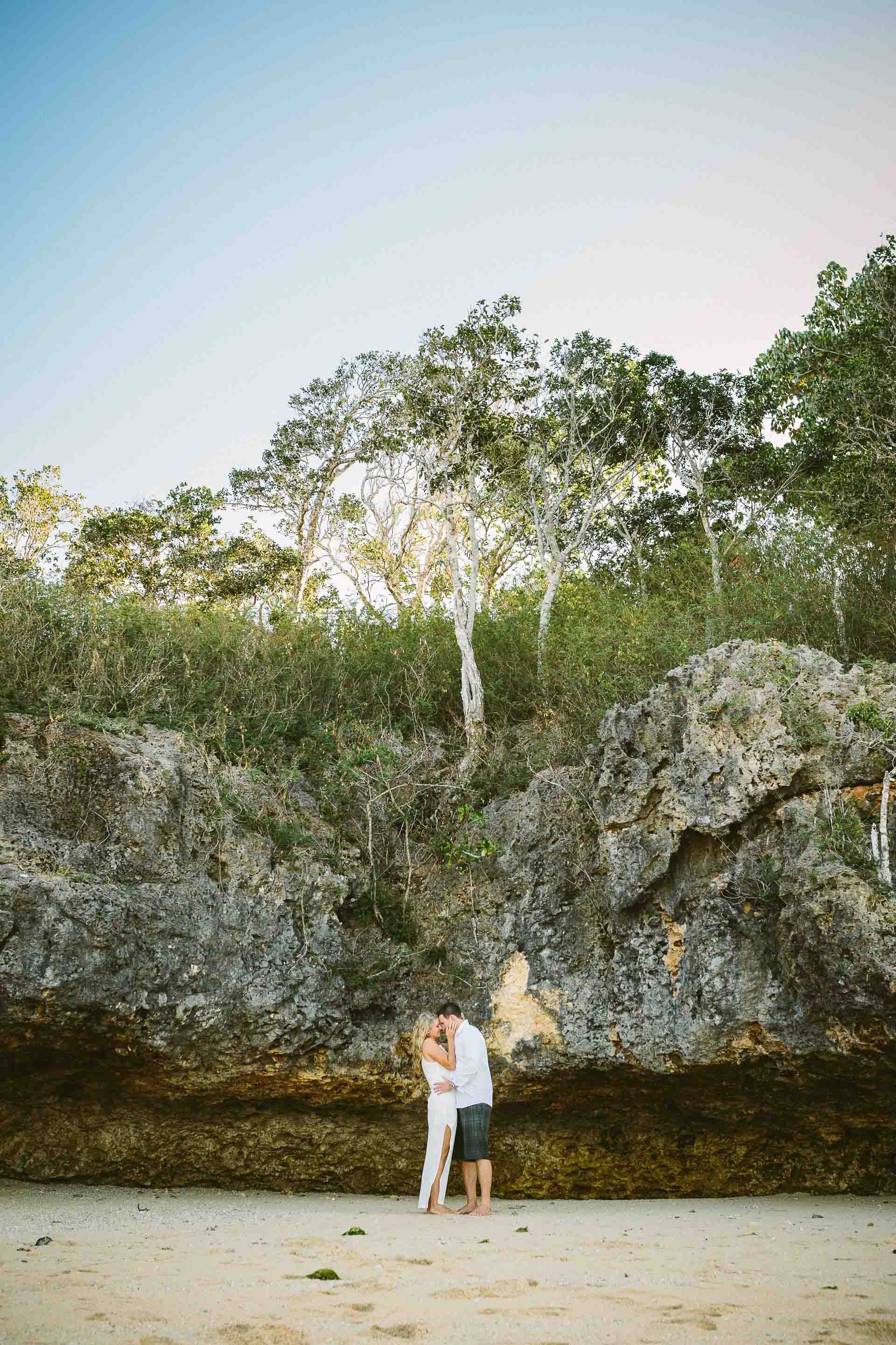 bride and groom kissing with rocks behind them