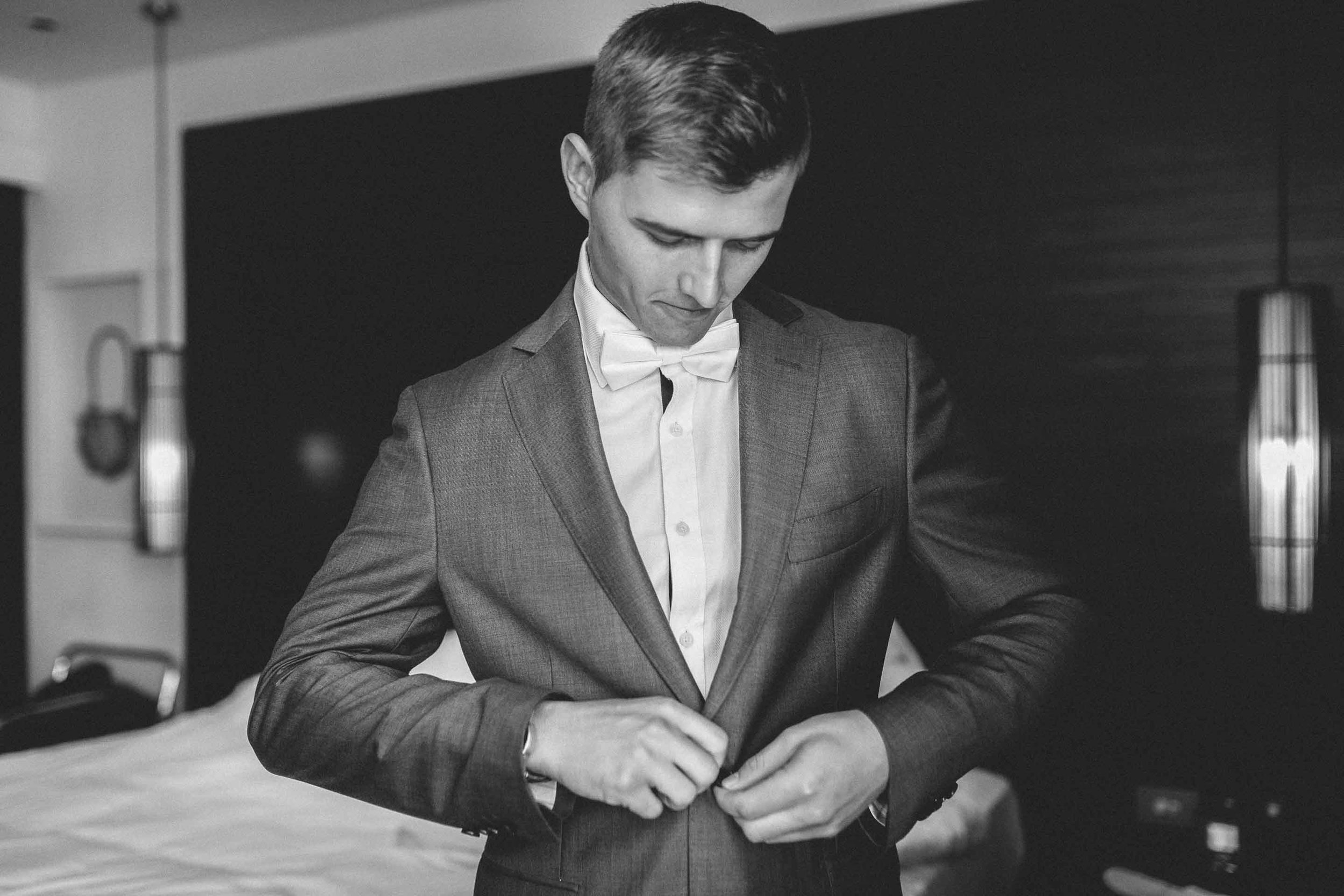 Handsome Groom buttons up his Suit Jacket. 