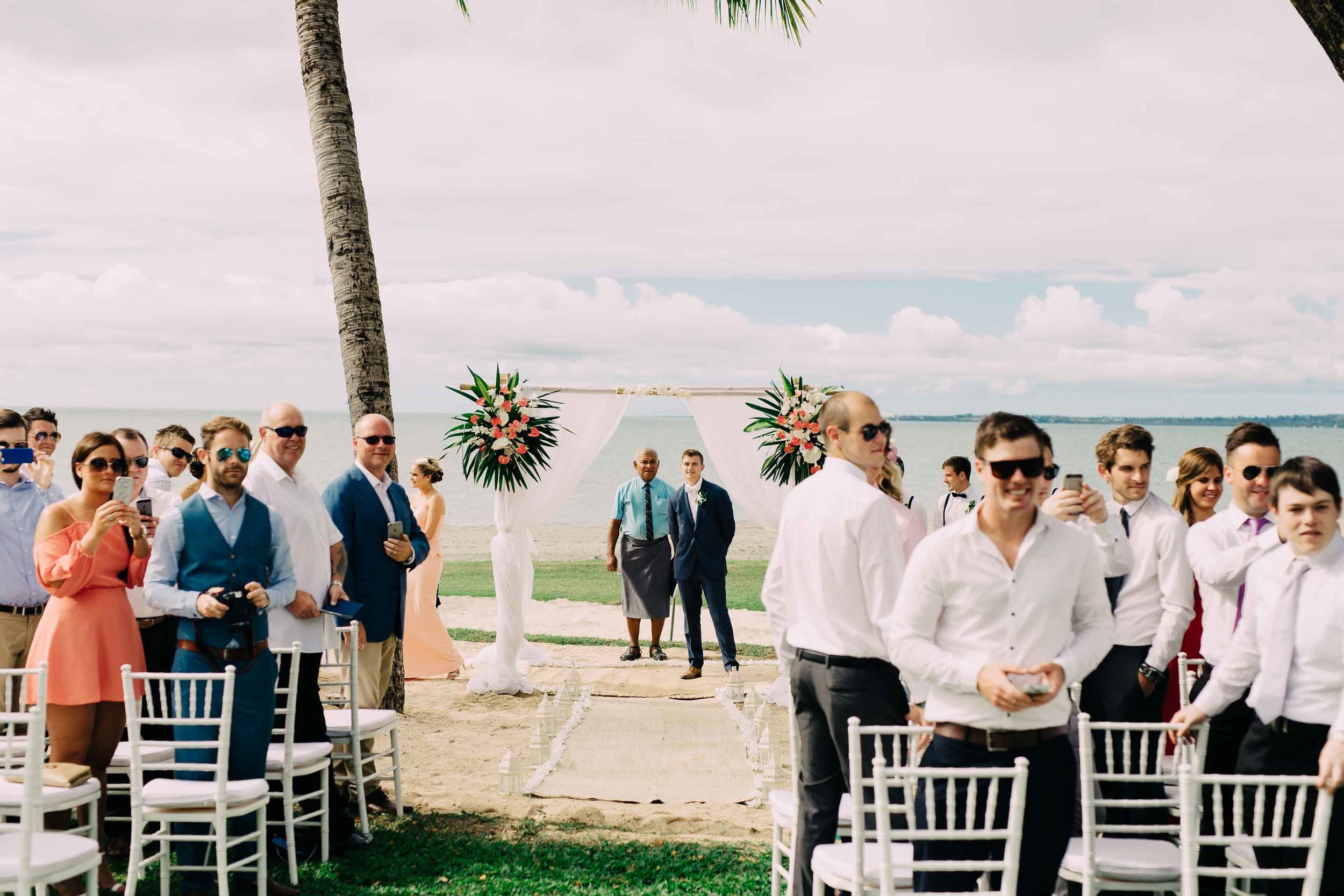 Wedding guests and groom watch and wait in anticipation of the Bride's arrival.