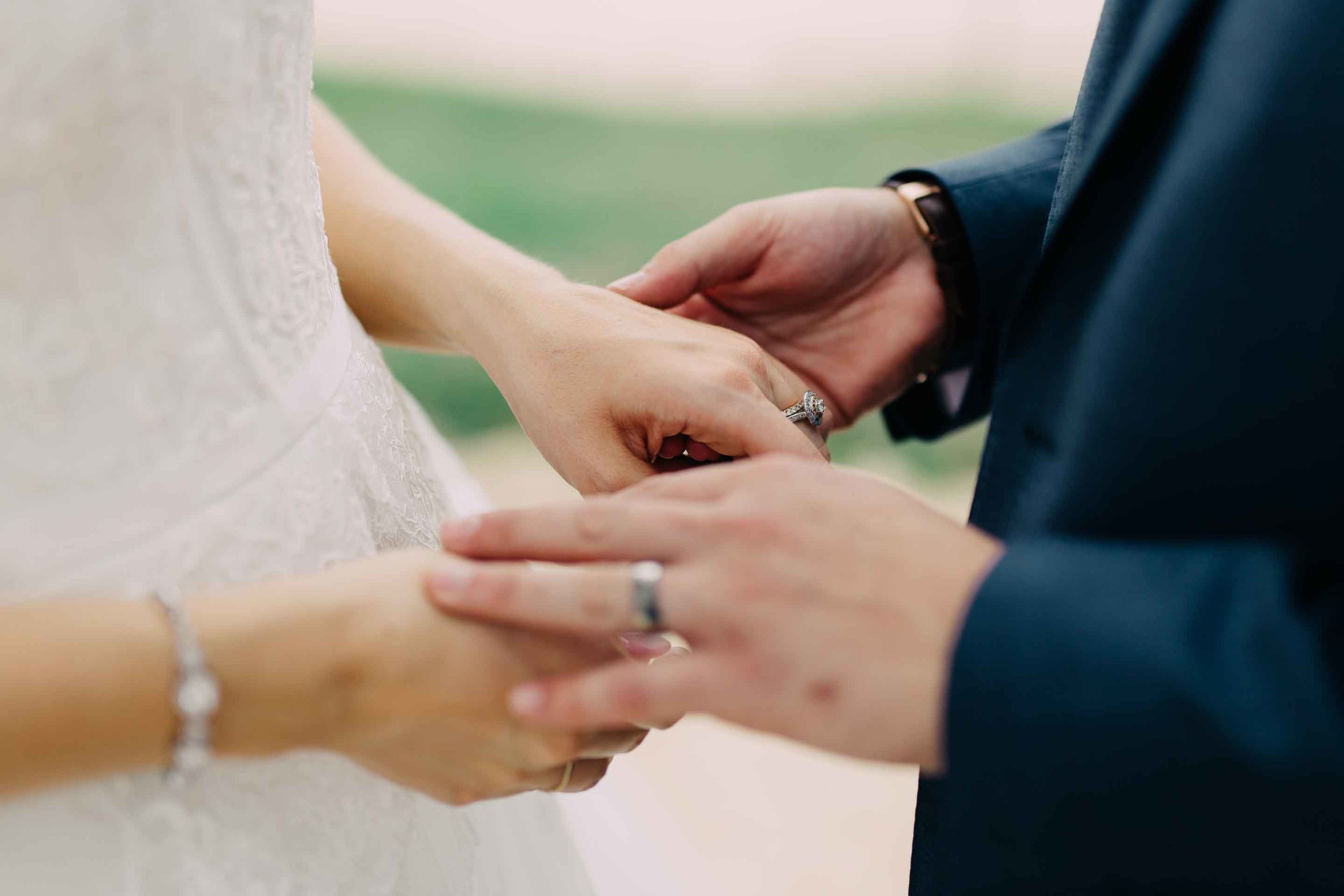 Newlyweds husband and wife hold hands and admire their rings after the marriage. 