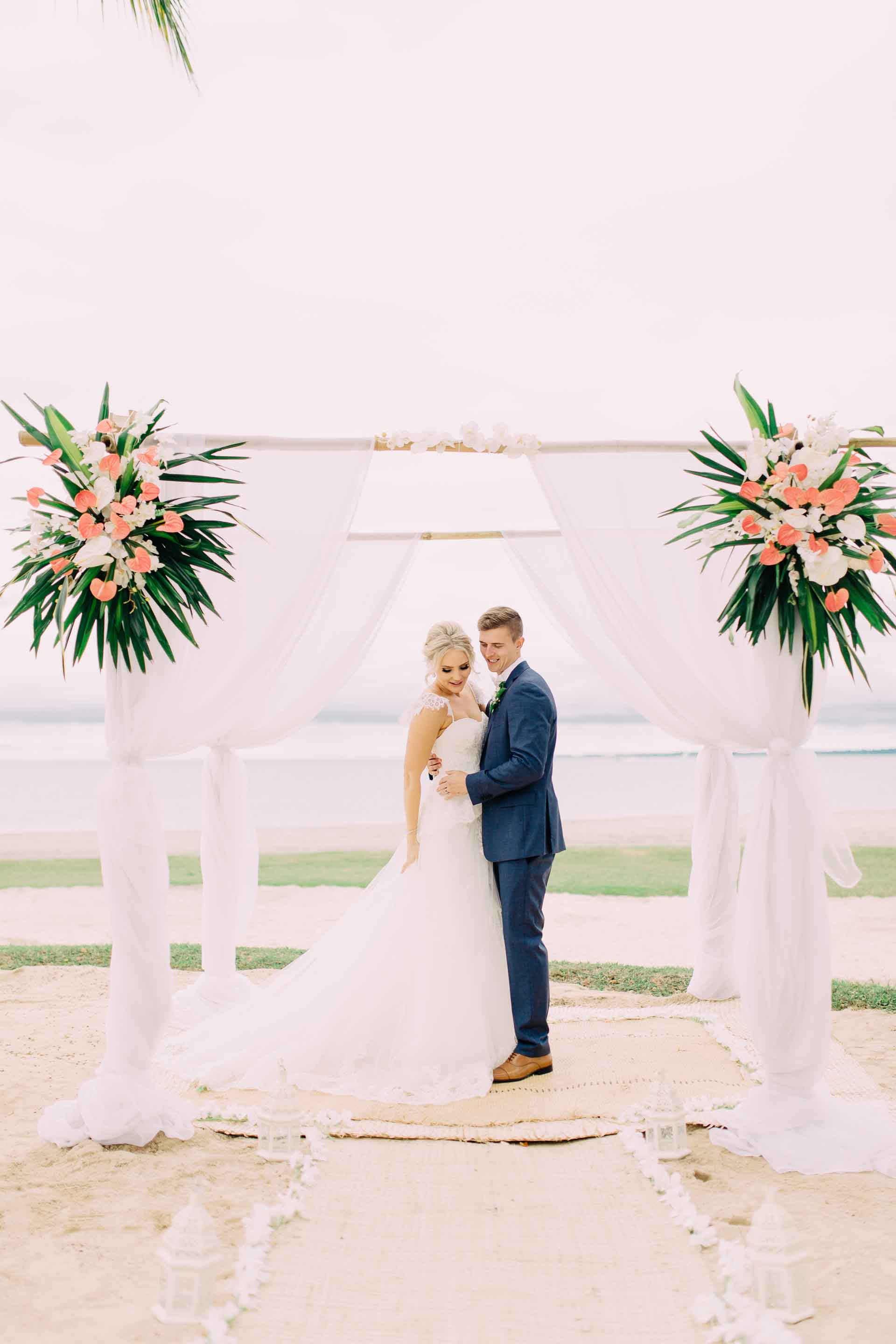 Newlyweds pose with their stunning tropical wedding ceremony arch on the Hilton Fiji Beach. 