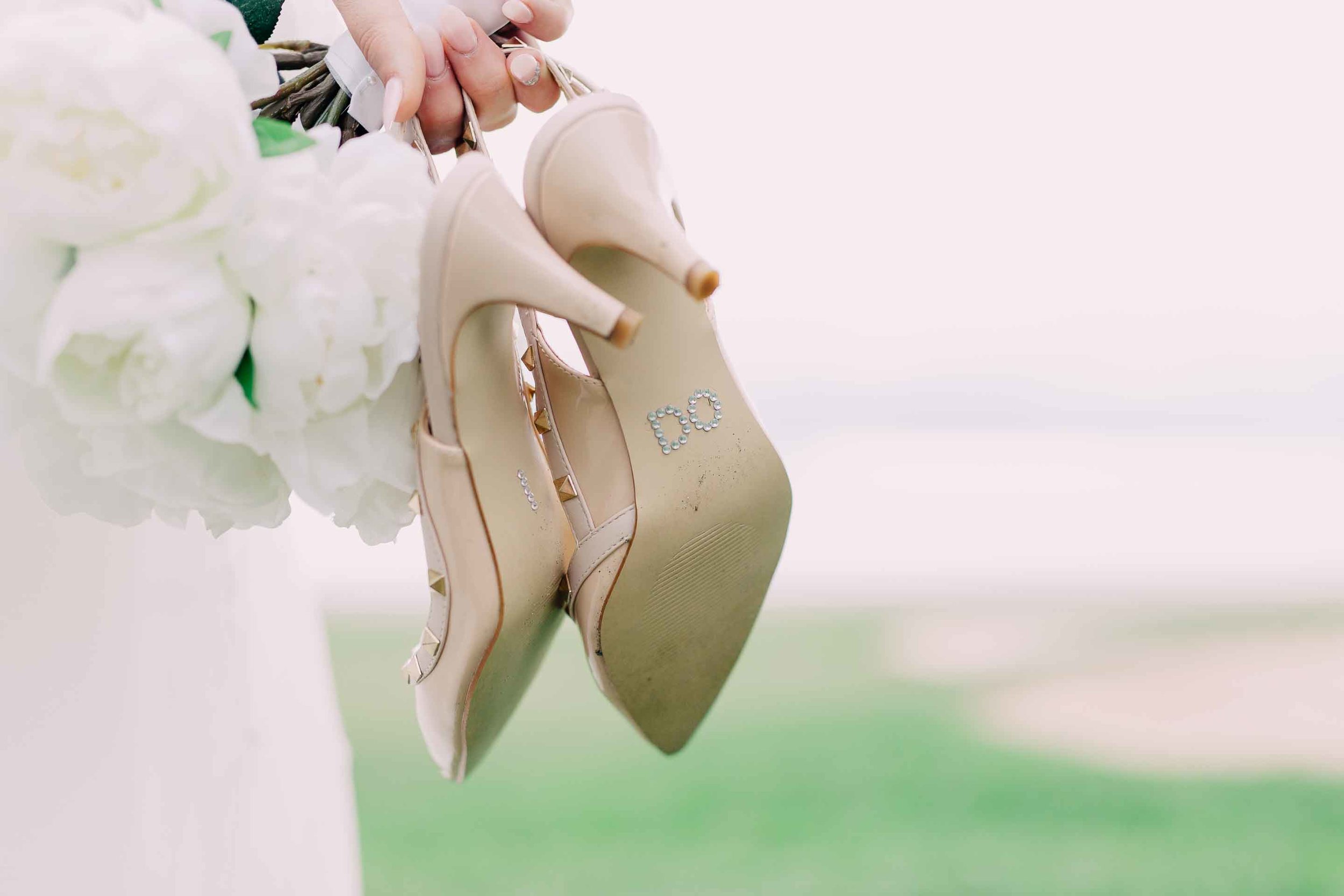 Artificial white peony wedding bouquet and bride's shoes with I Do on the soles in rhinestones. Wedding shoes are Nude Valentino studded heels.