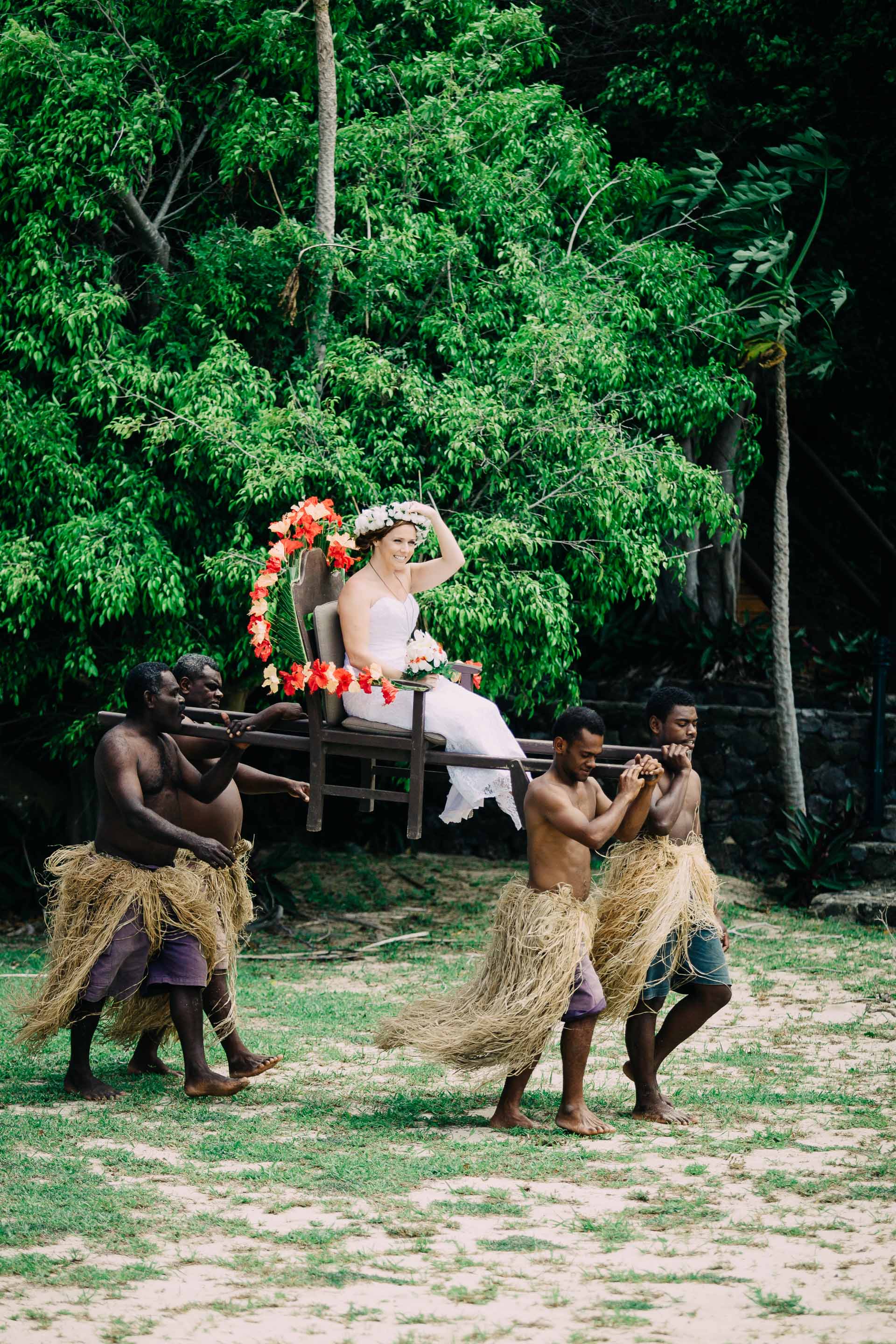 the bride being carried to the altar by Fijian warriors
