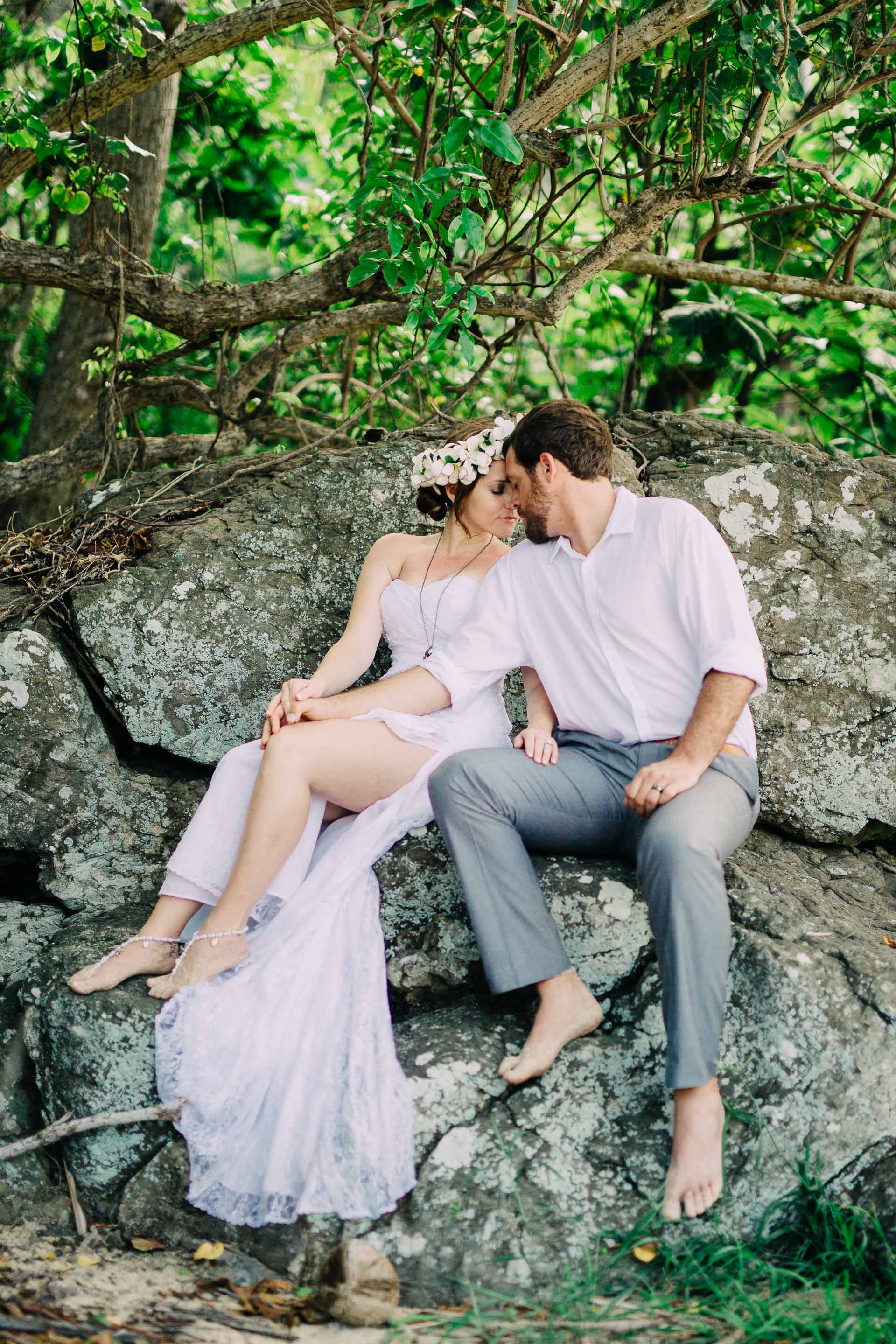 The newlyweds sitting on a rock together in the bush
