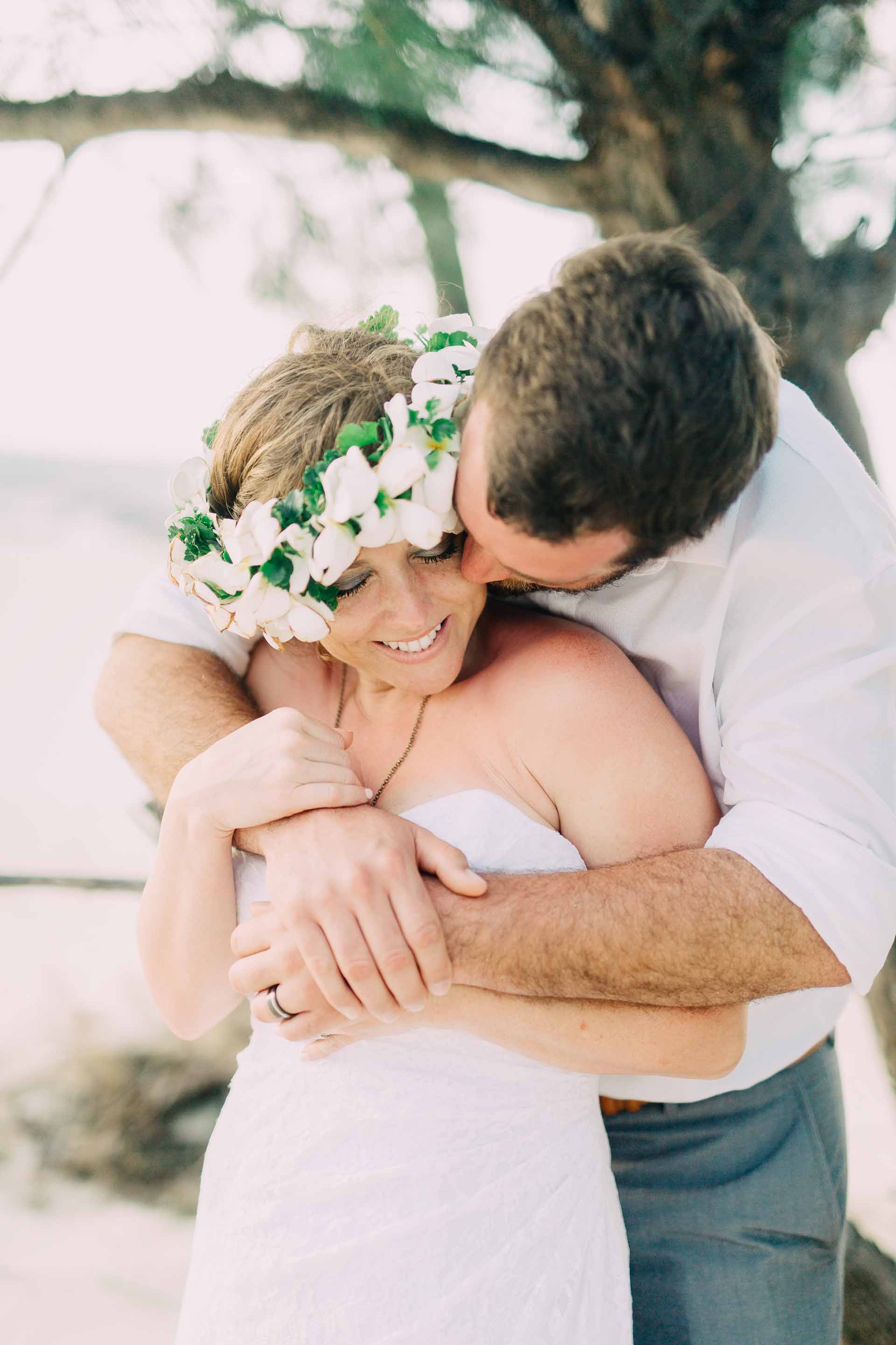 the groom hugging the bride on the beach