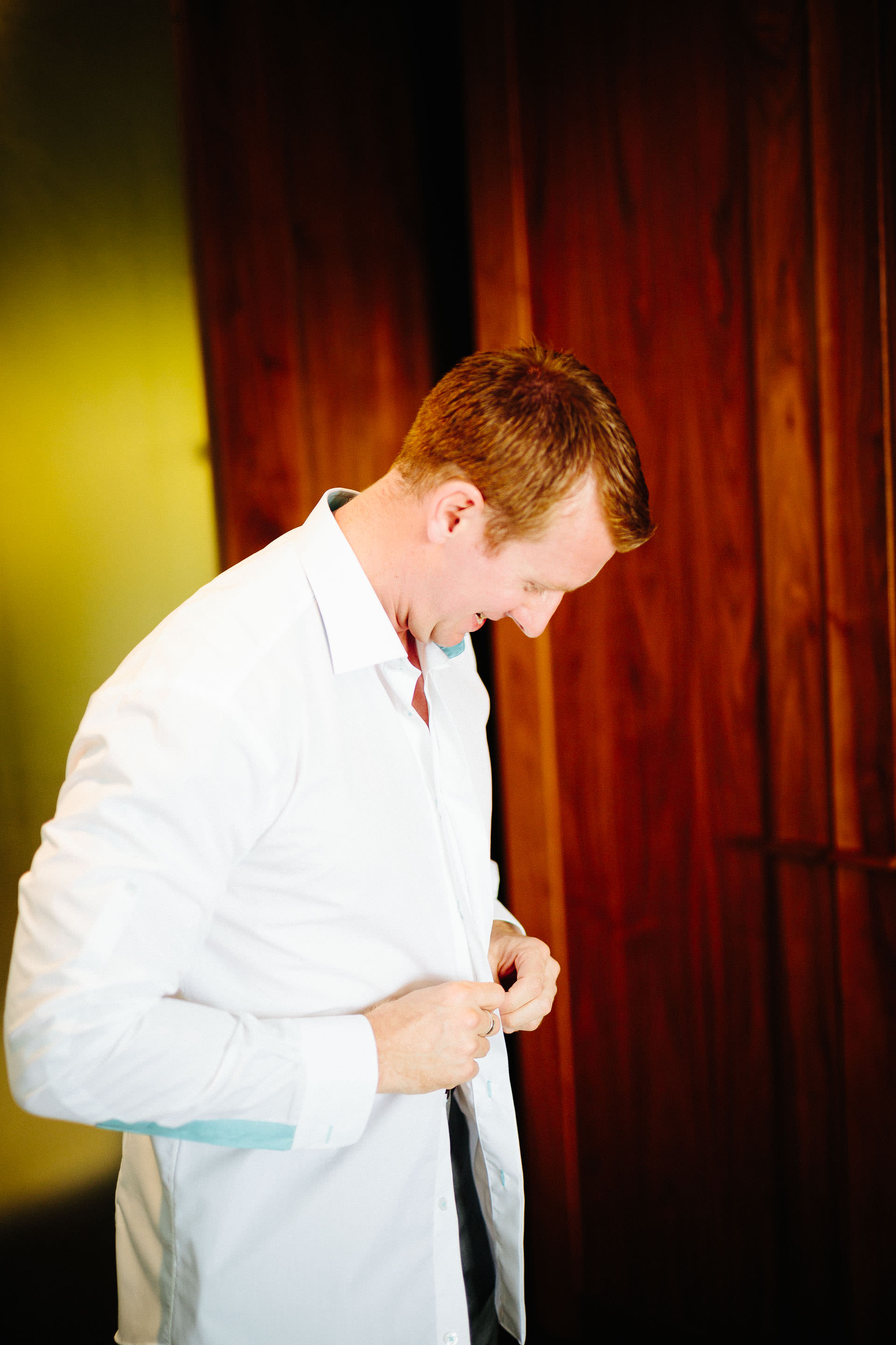 The groom buttoning up his shirt.