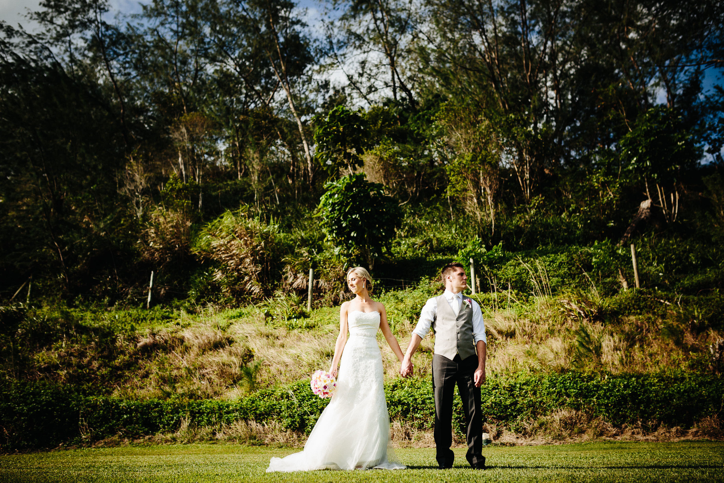 bride and groom holding hands in field