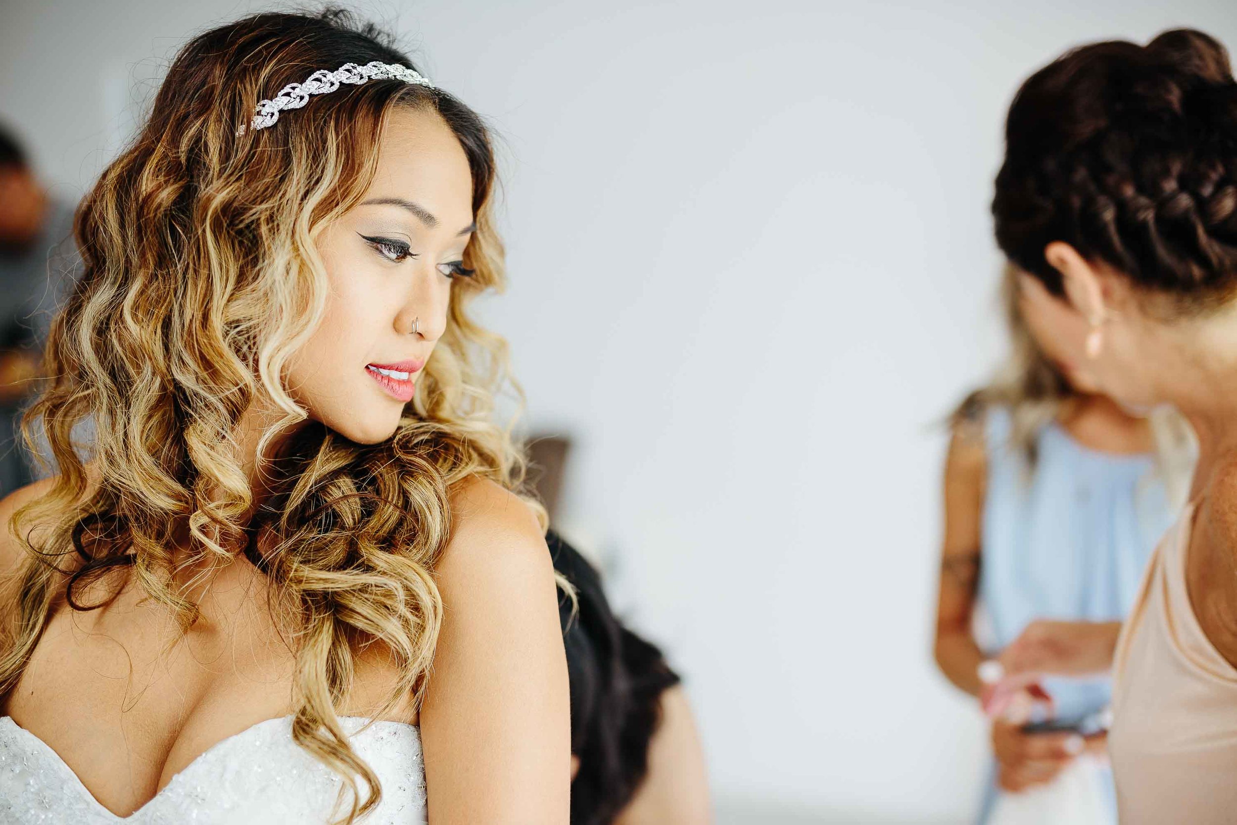 bride looking over shoulder as dress is done up