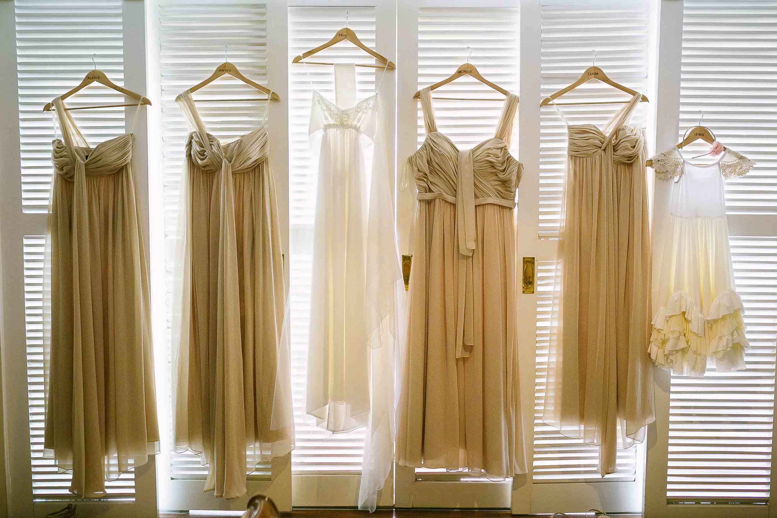 wedding gown and bridesmaid dresses hung from white shutters