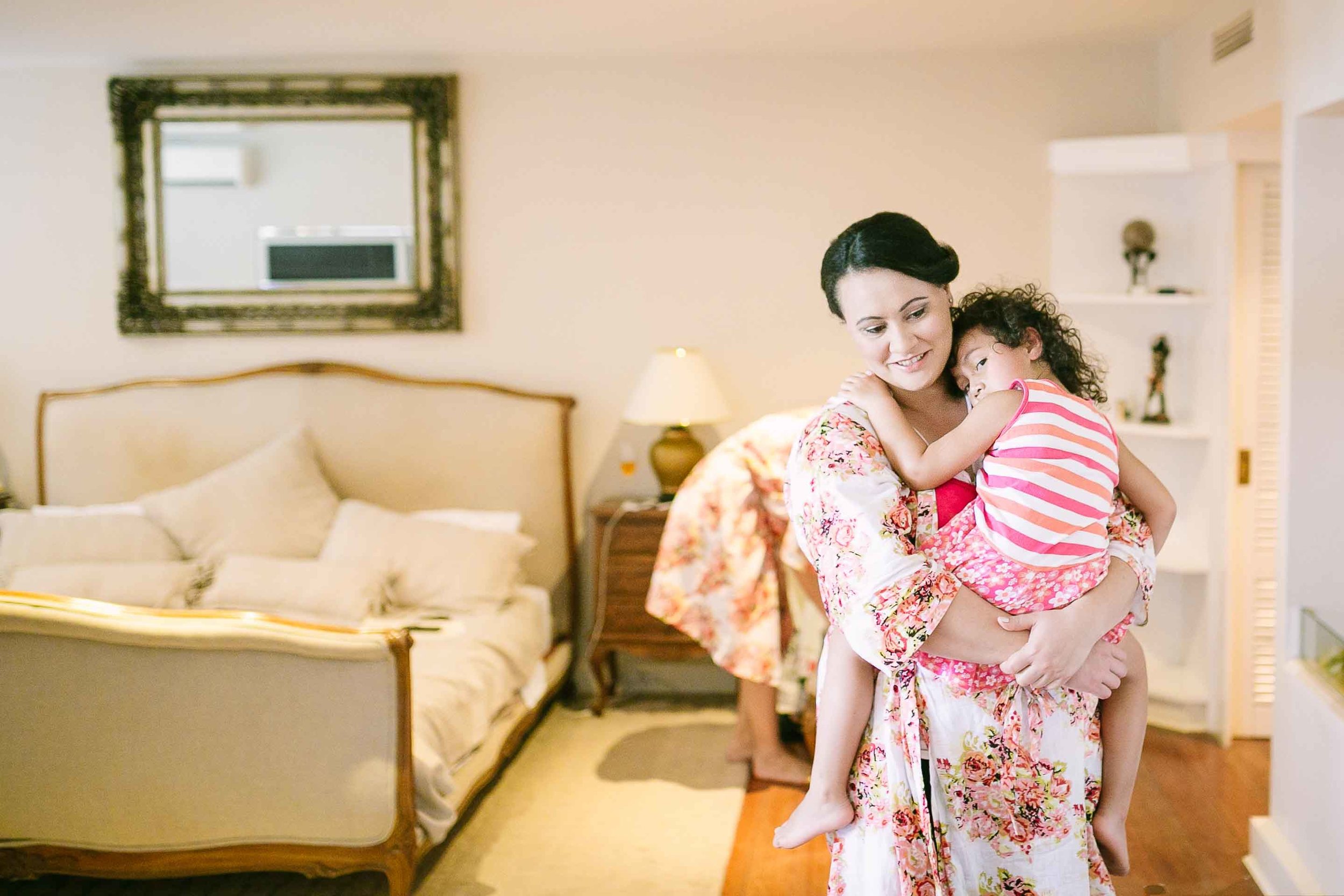 bridesmaid carrying her daughter as they get ready