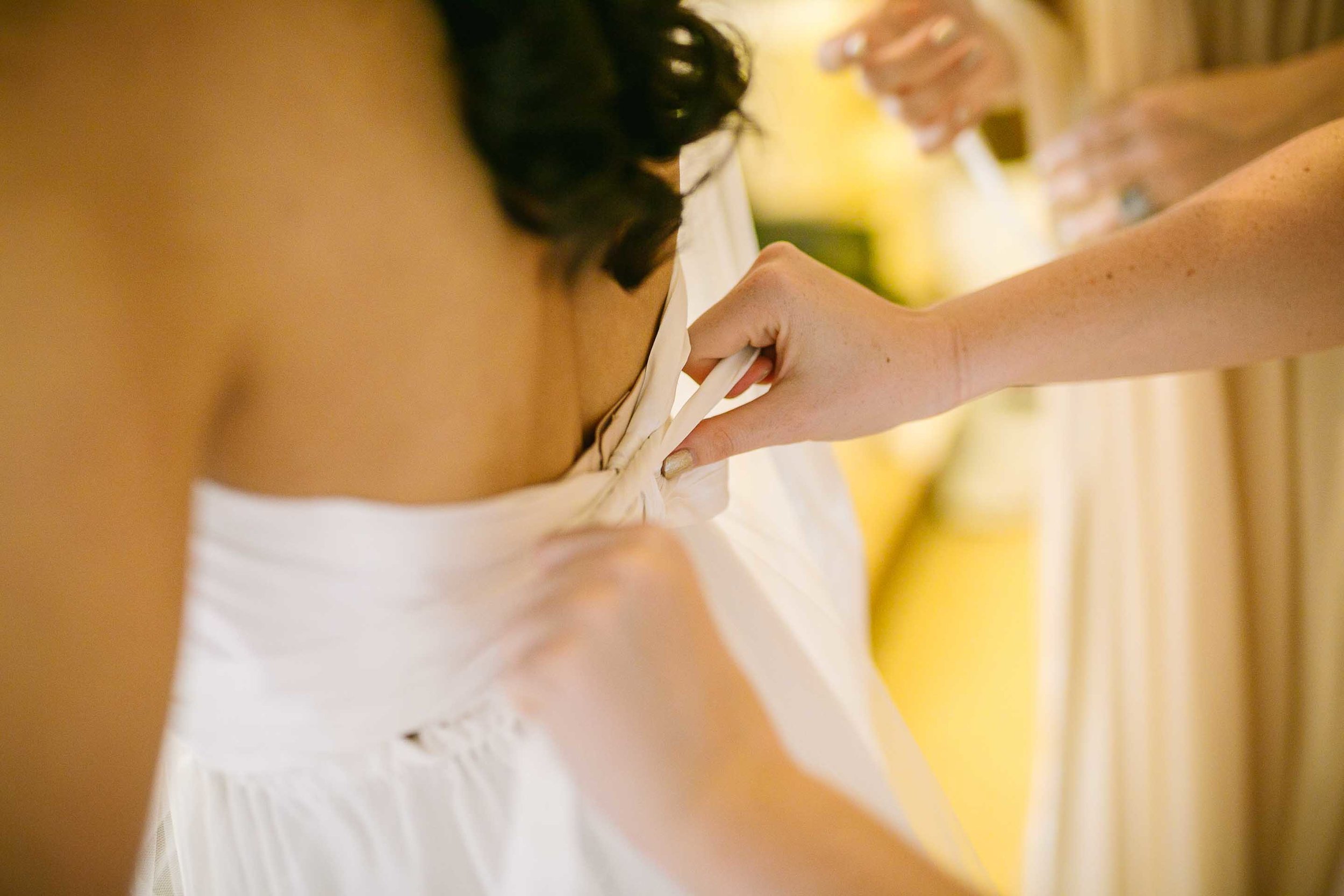 bridesmaids helping the bride into her wedding gown