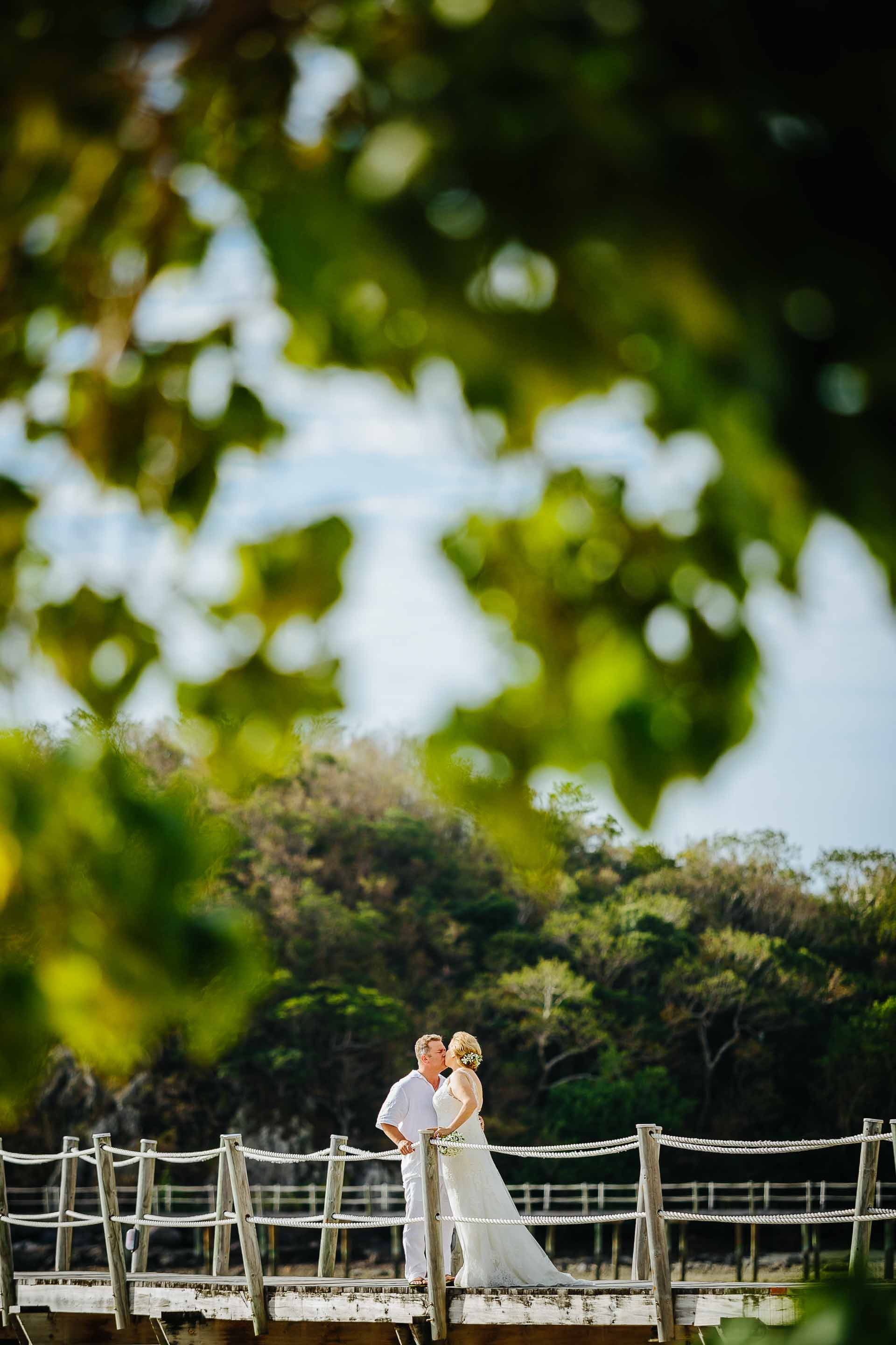 the couple walking down the pier through the trees
