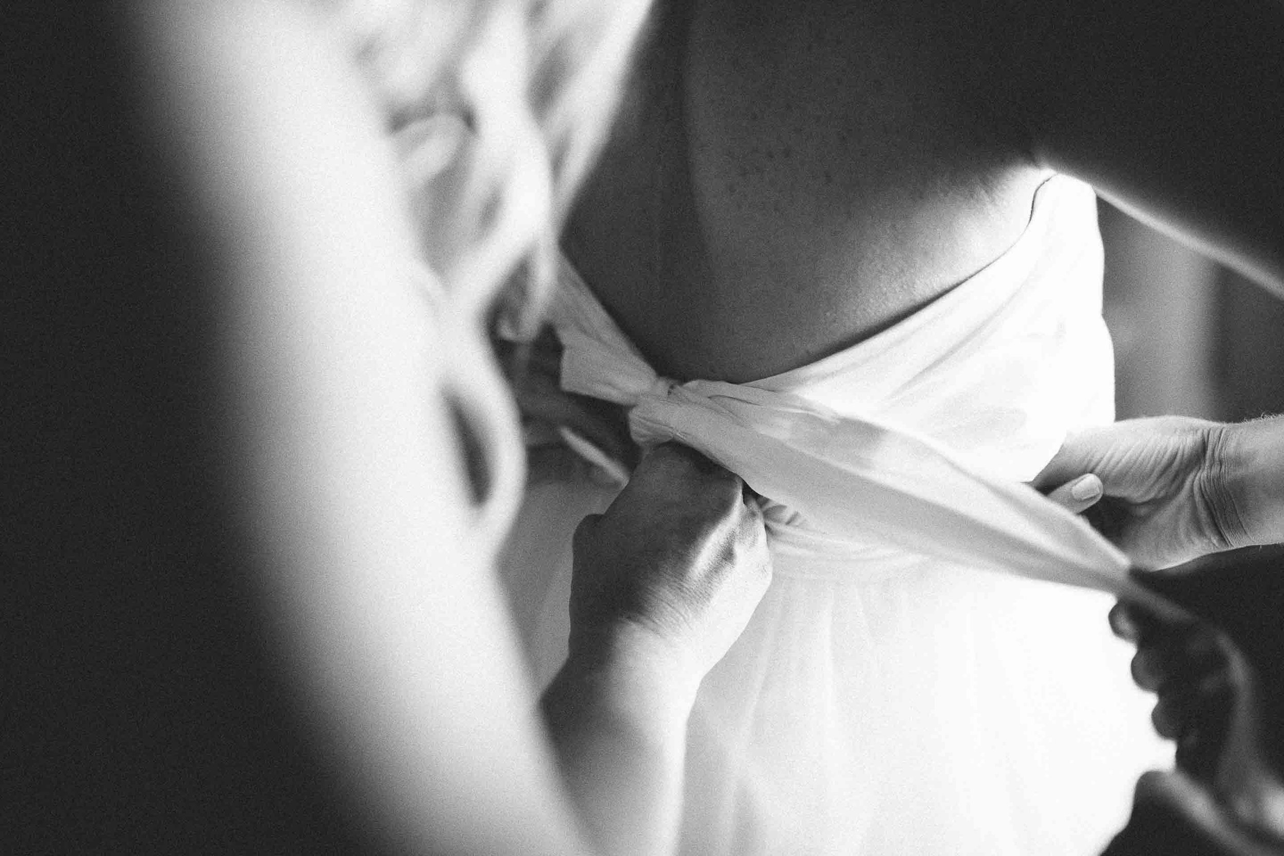 maid of honor tying up the straps of the brides dress