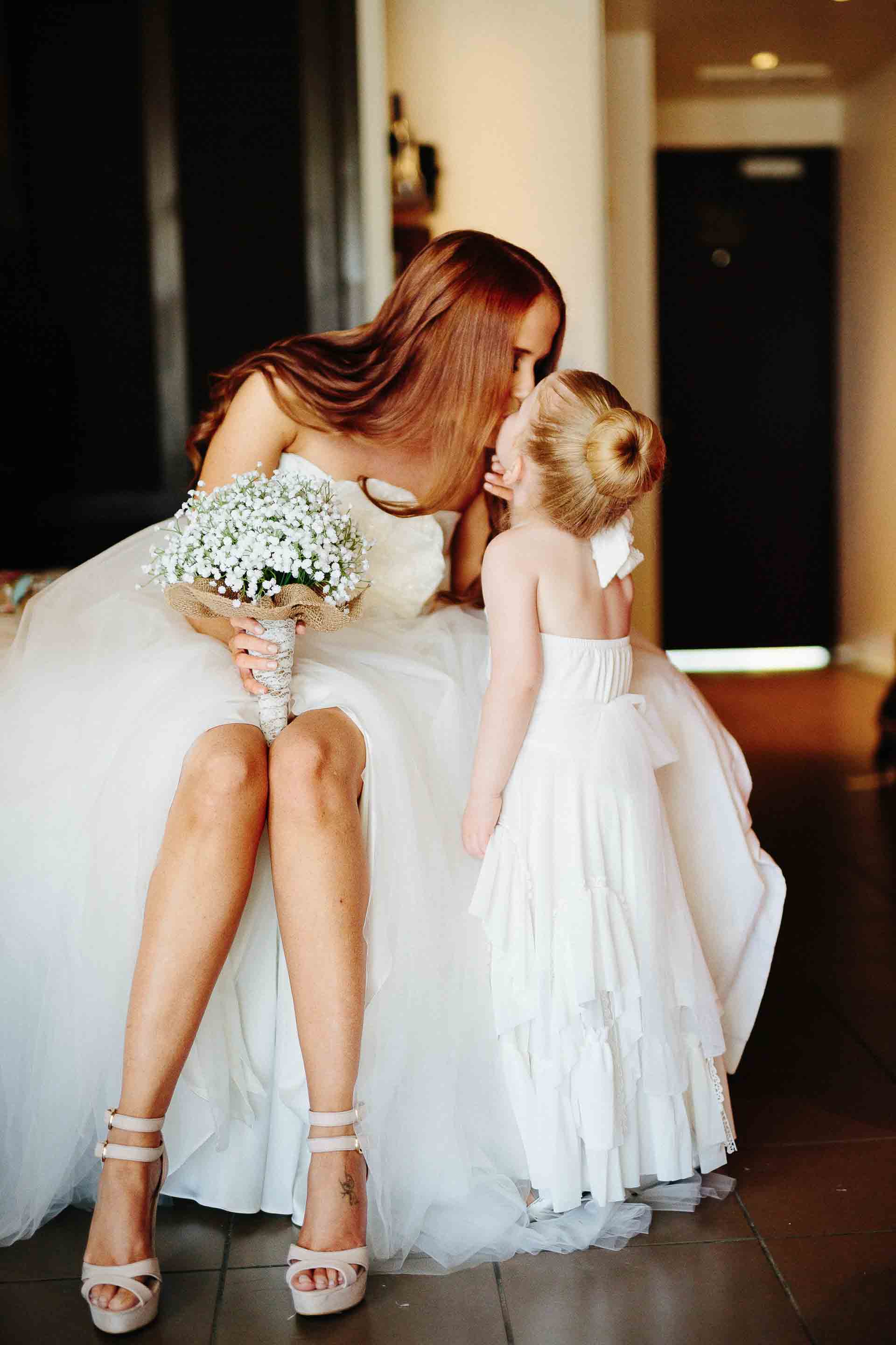the bride receiving a kiss from the flower girl