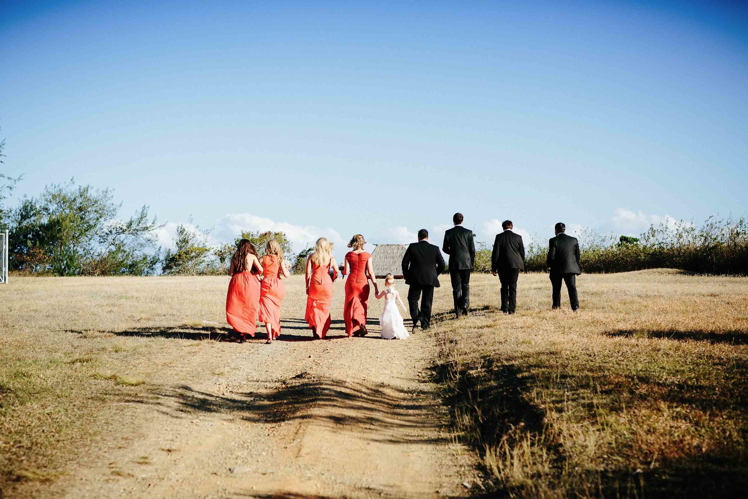 the bridal party walking off along a dusty dirt road