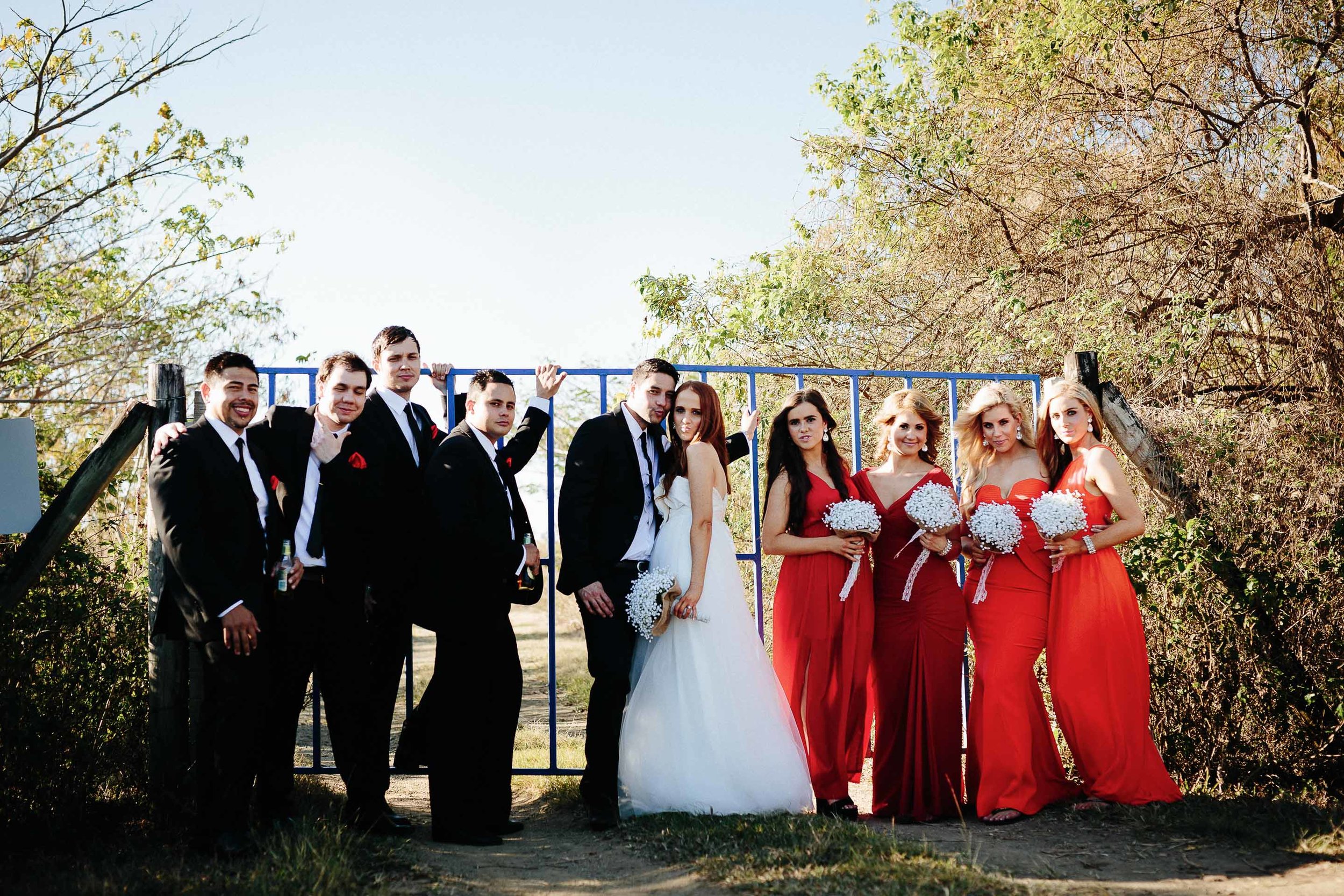 the bridal party sharing a light moment next to a blue gate