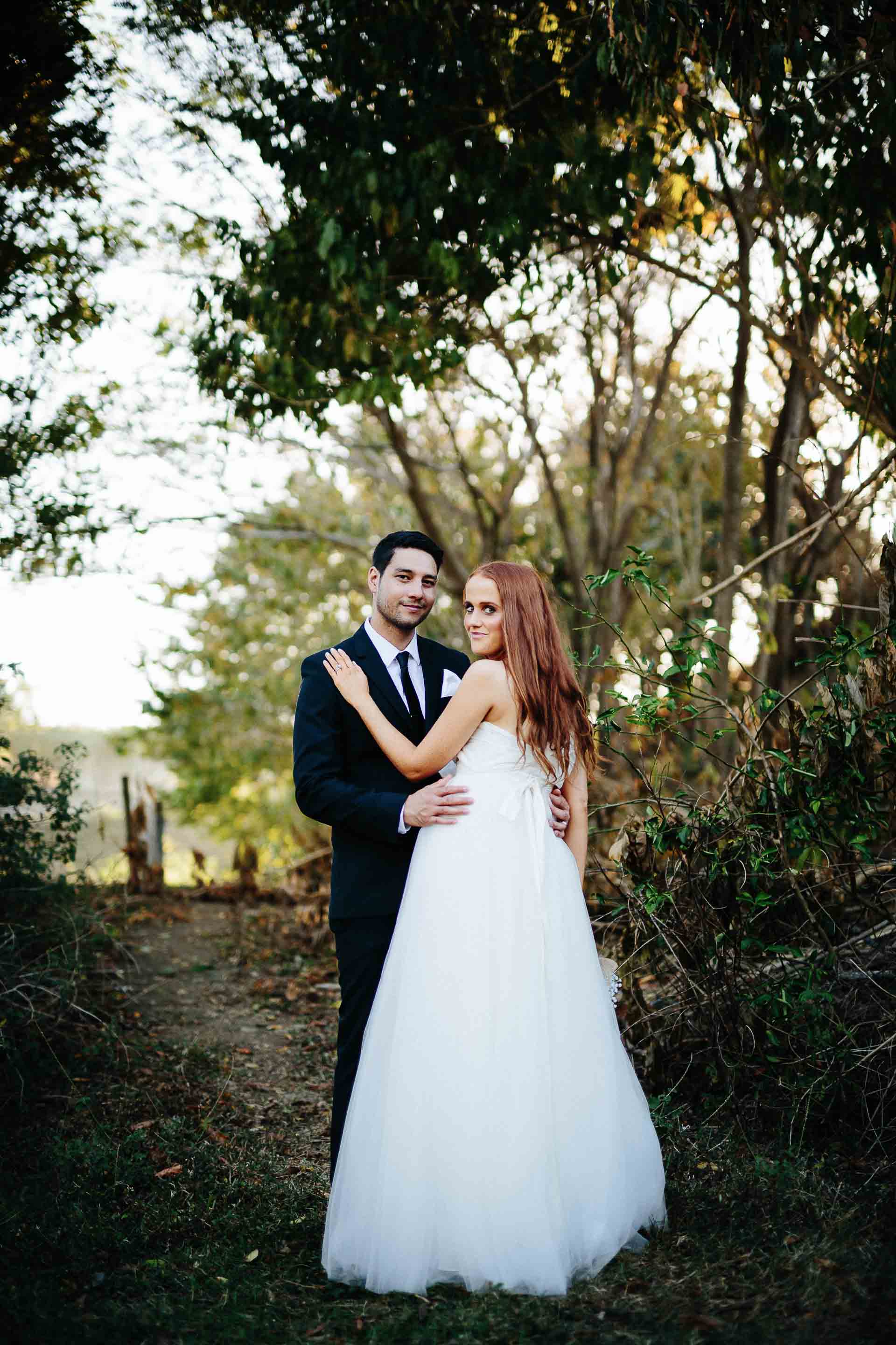 the couple holding each other with trees behind them