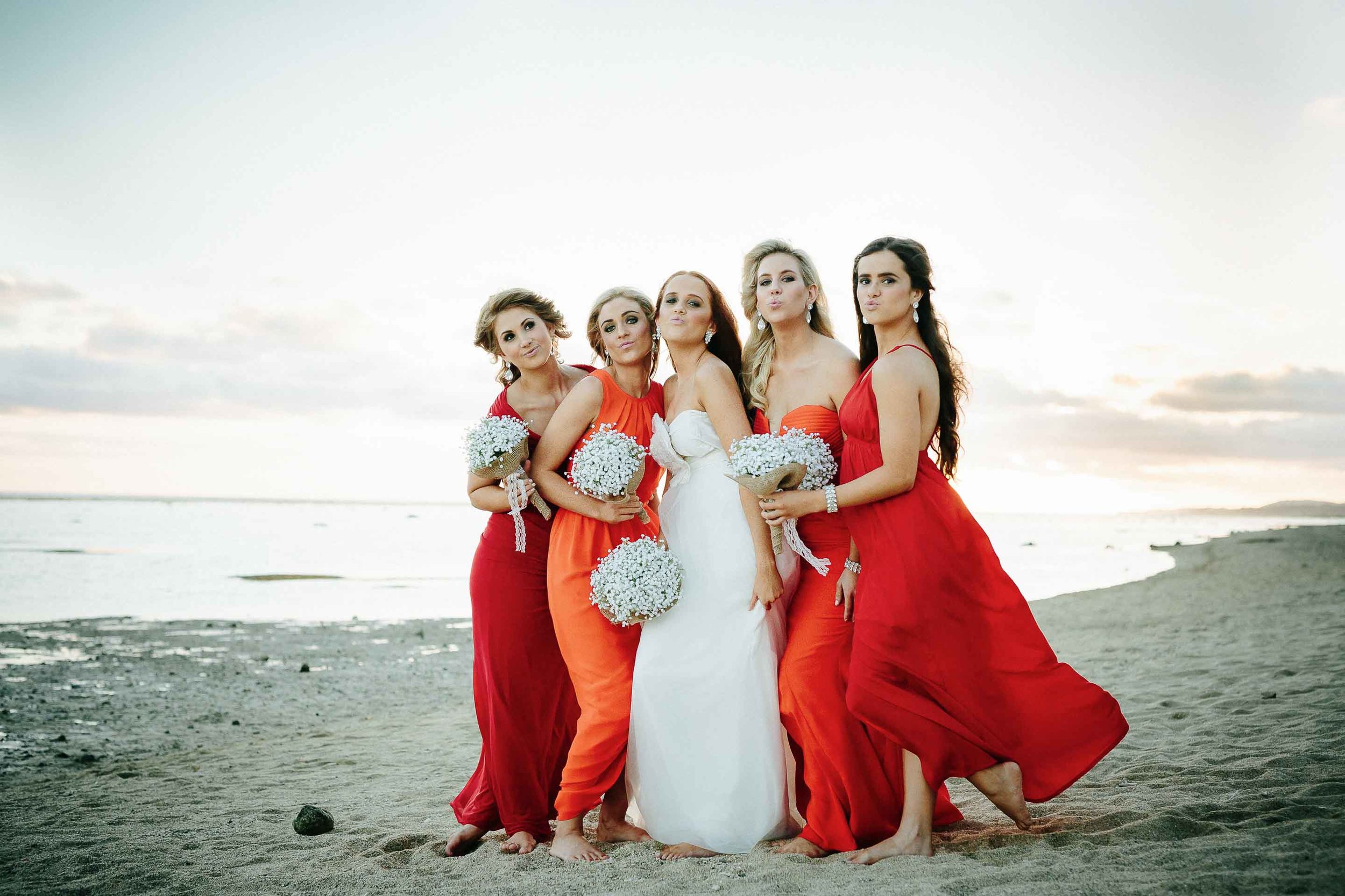 bride and bridesmaids pulling a funny face on the beach at sunset