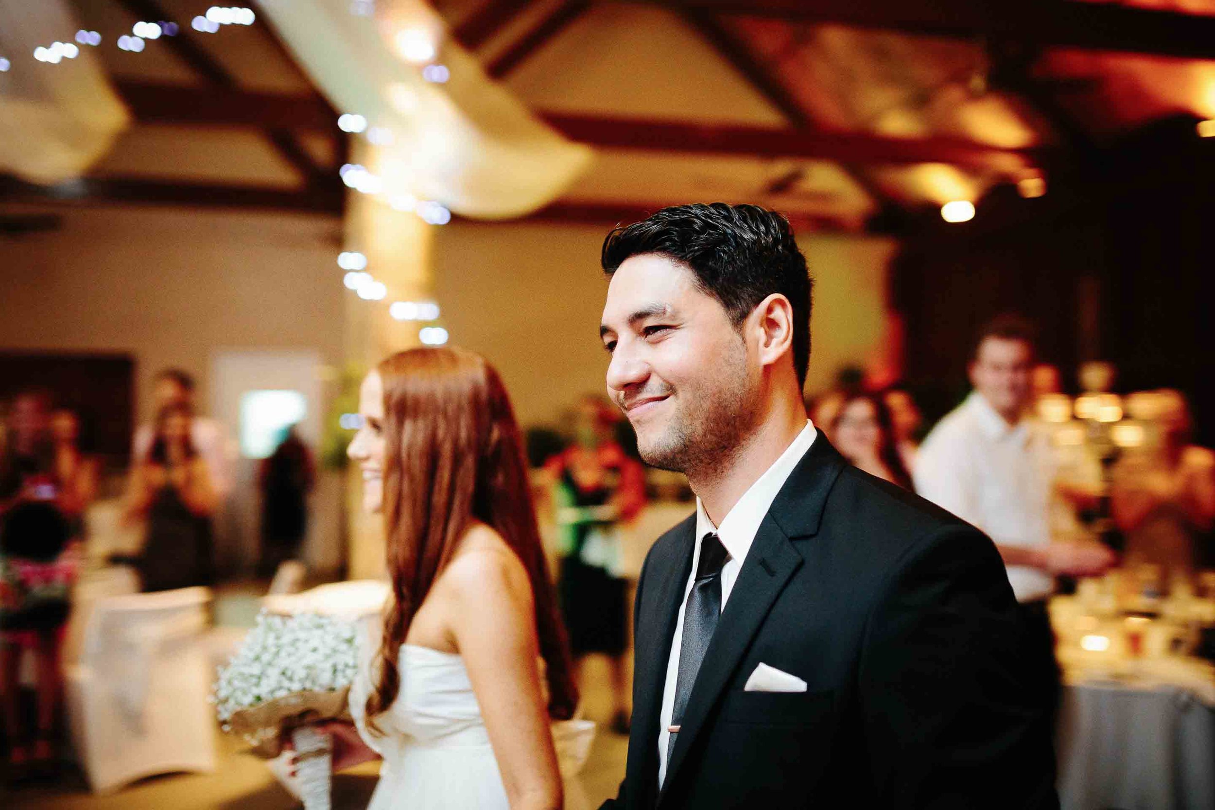 groom smiling as he leads his bride to their dinner table