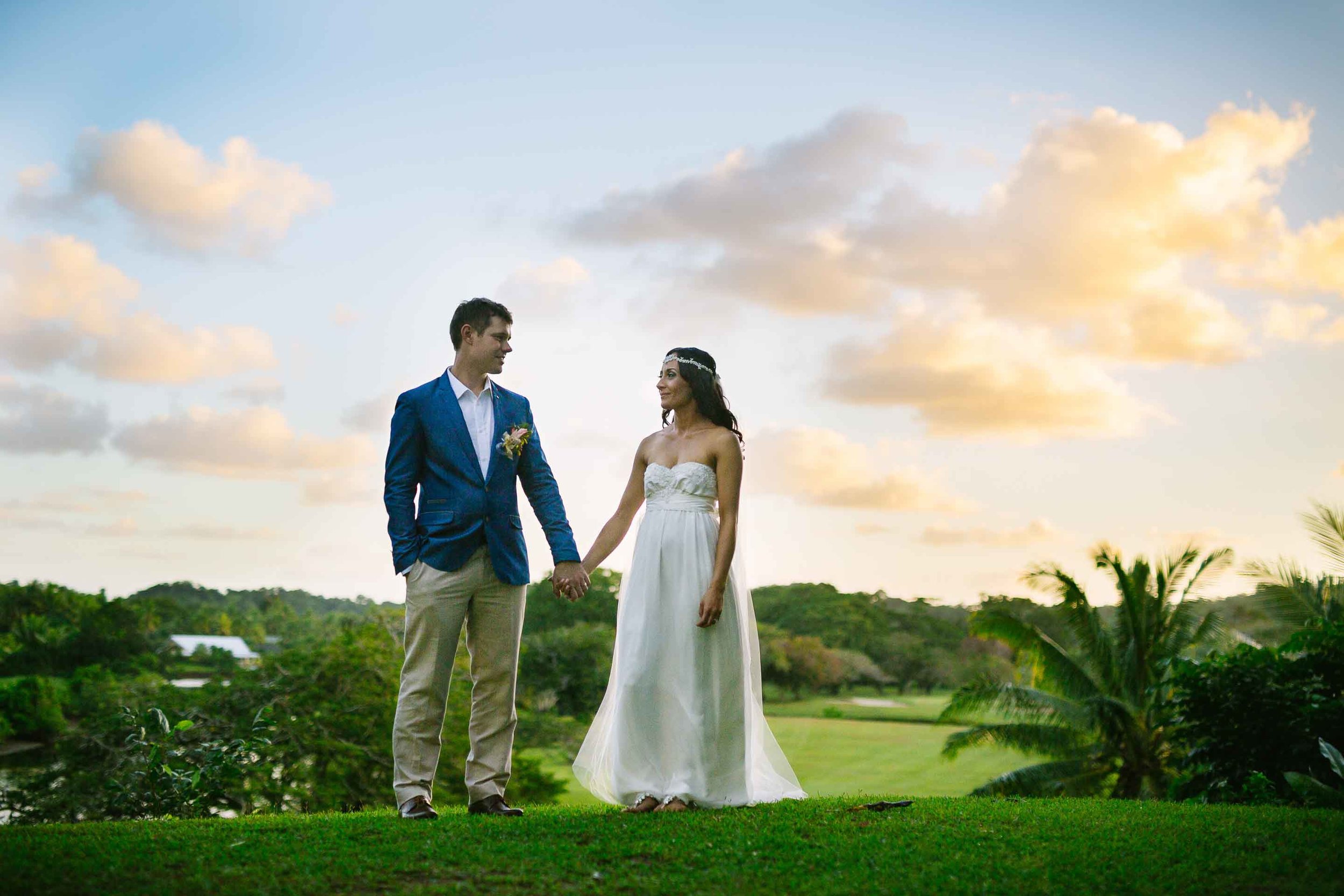 the newlyweds holding hands with golden clouds behind them