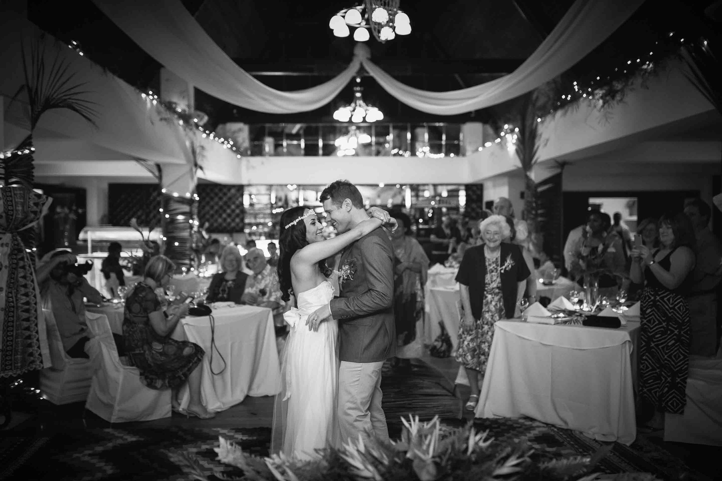 black and white of the first dance as husband and wife as guests look on