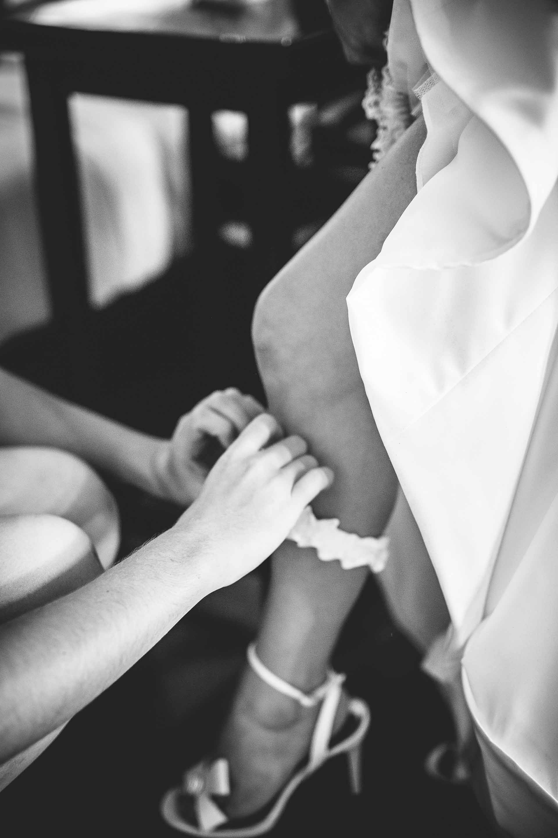 bridesmaid helping bride put on garter belt