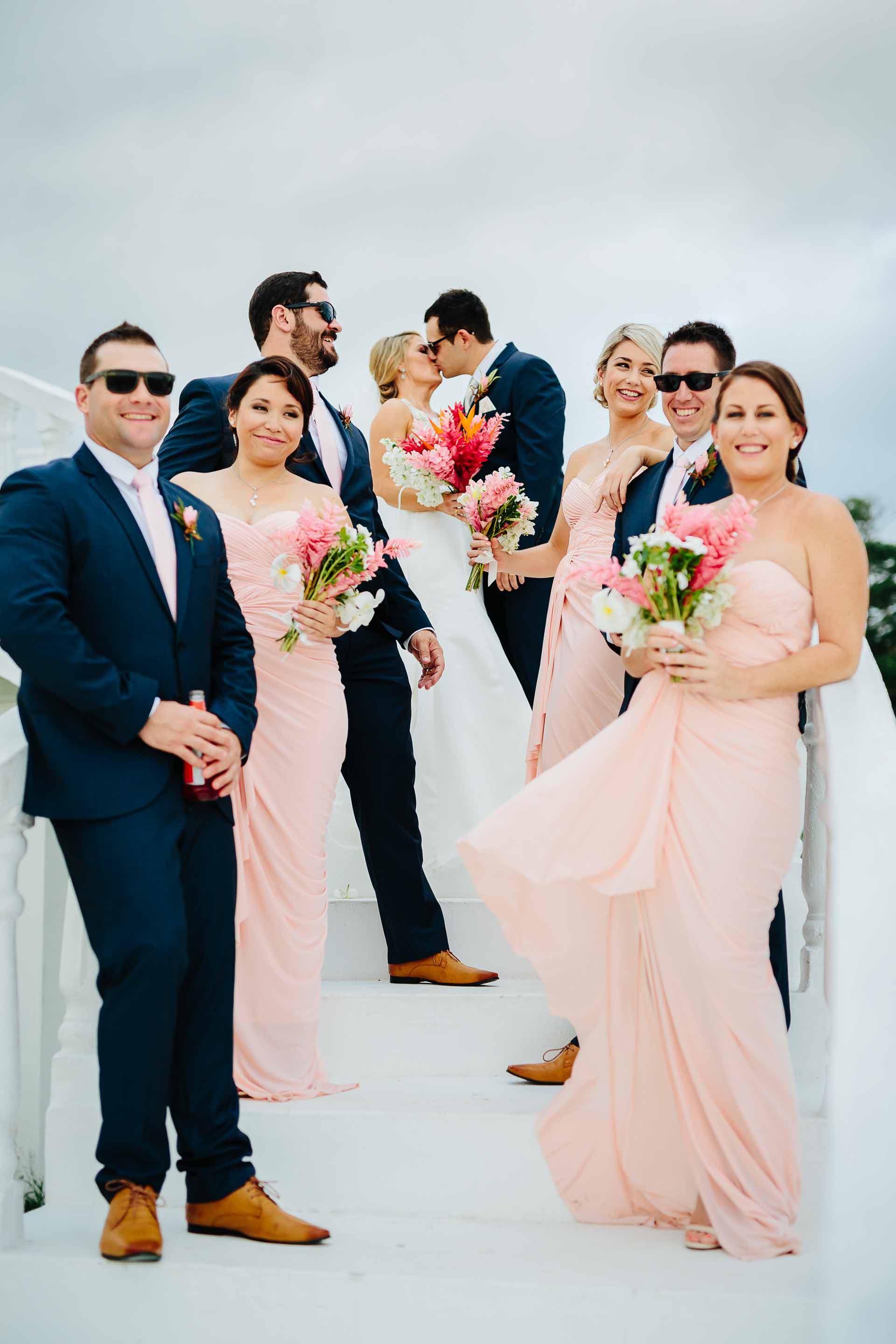 bridal party on stairs with couple kissing