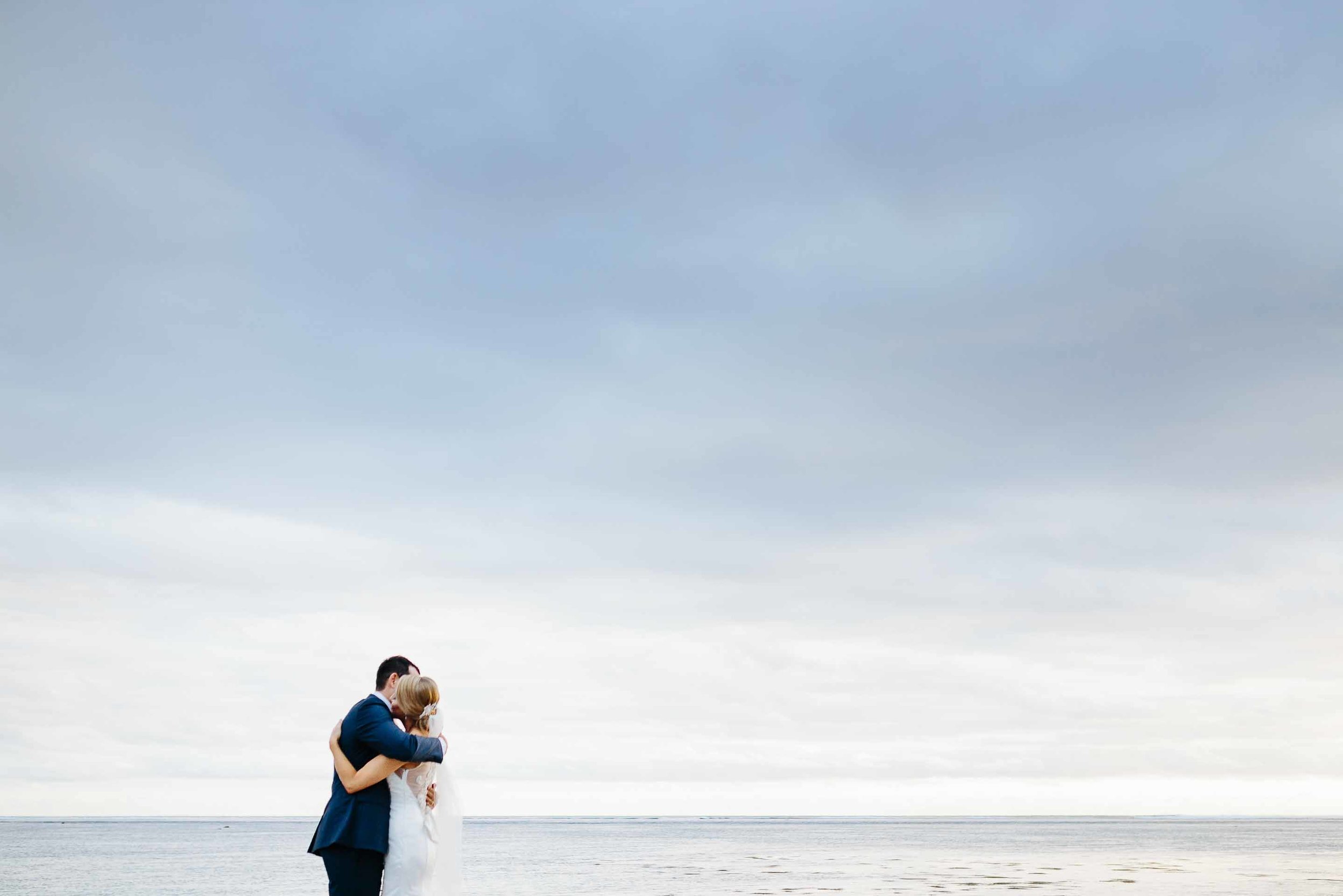 couple hugging with cloudy sky behind them