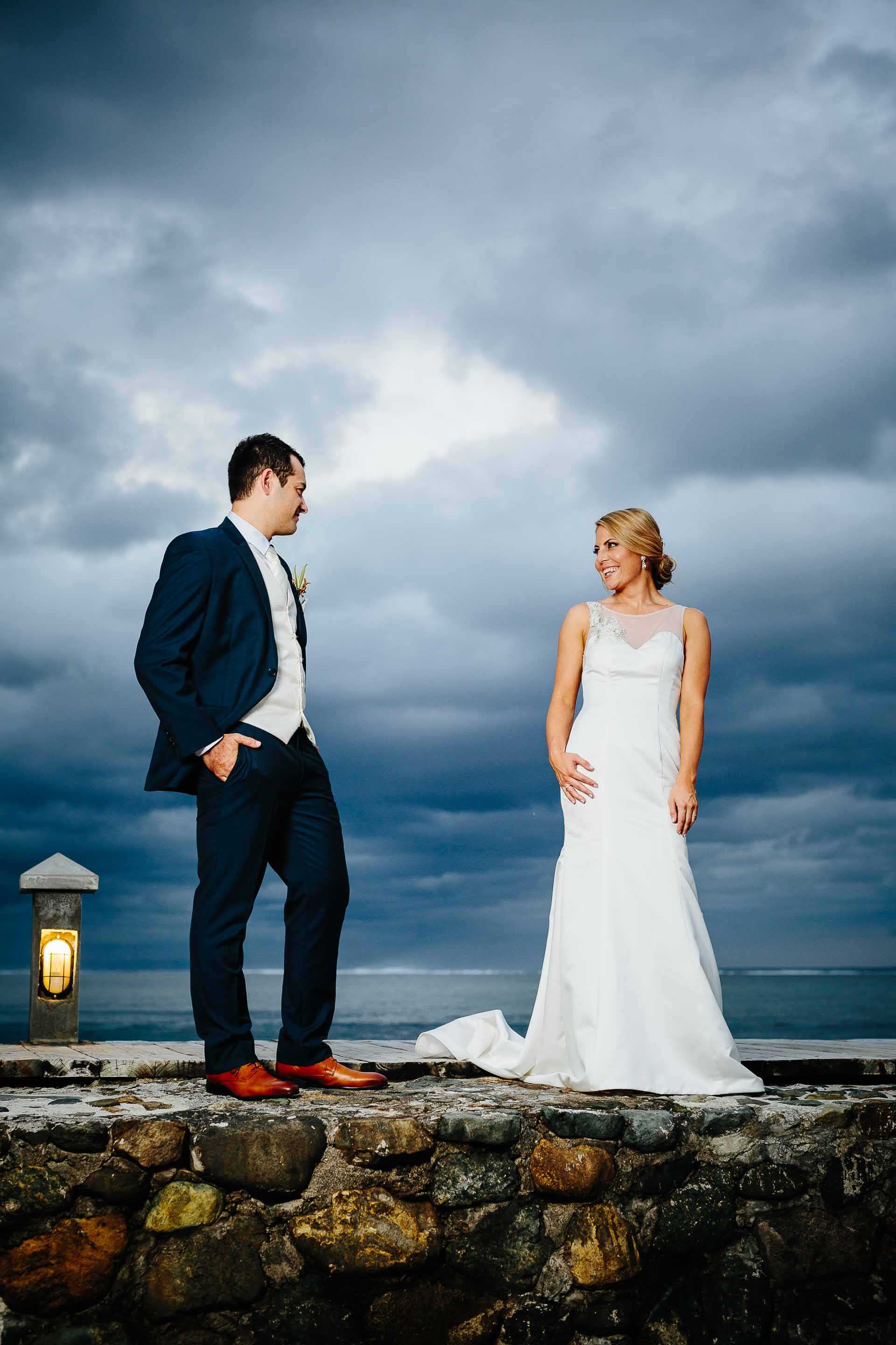 couple on pier with dramatic clouds behind them