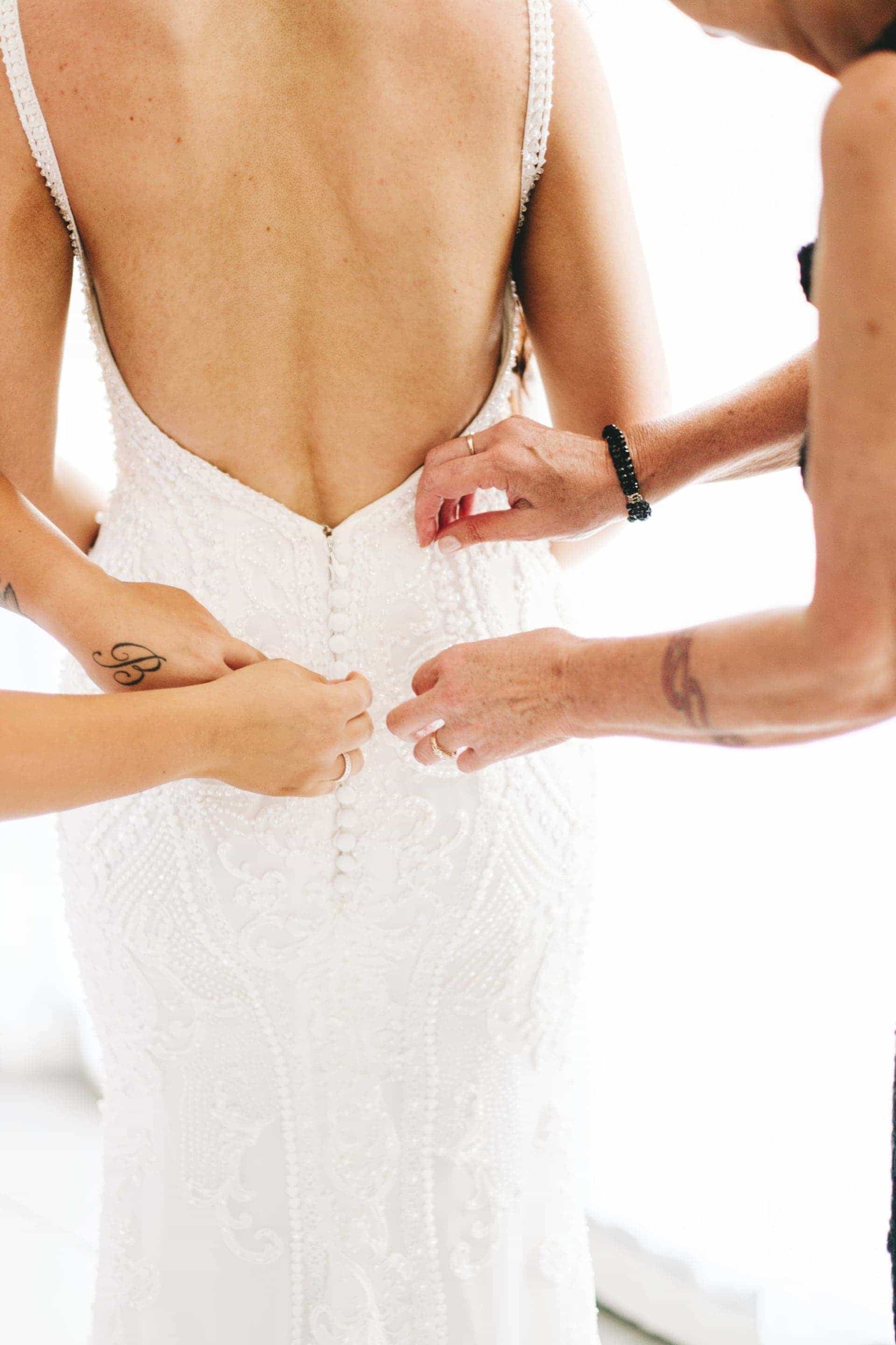 the bridesmaid and mother of the bride ad they adjust the brides dress.