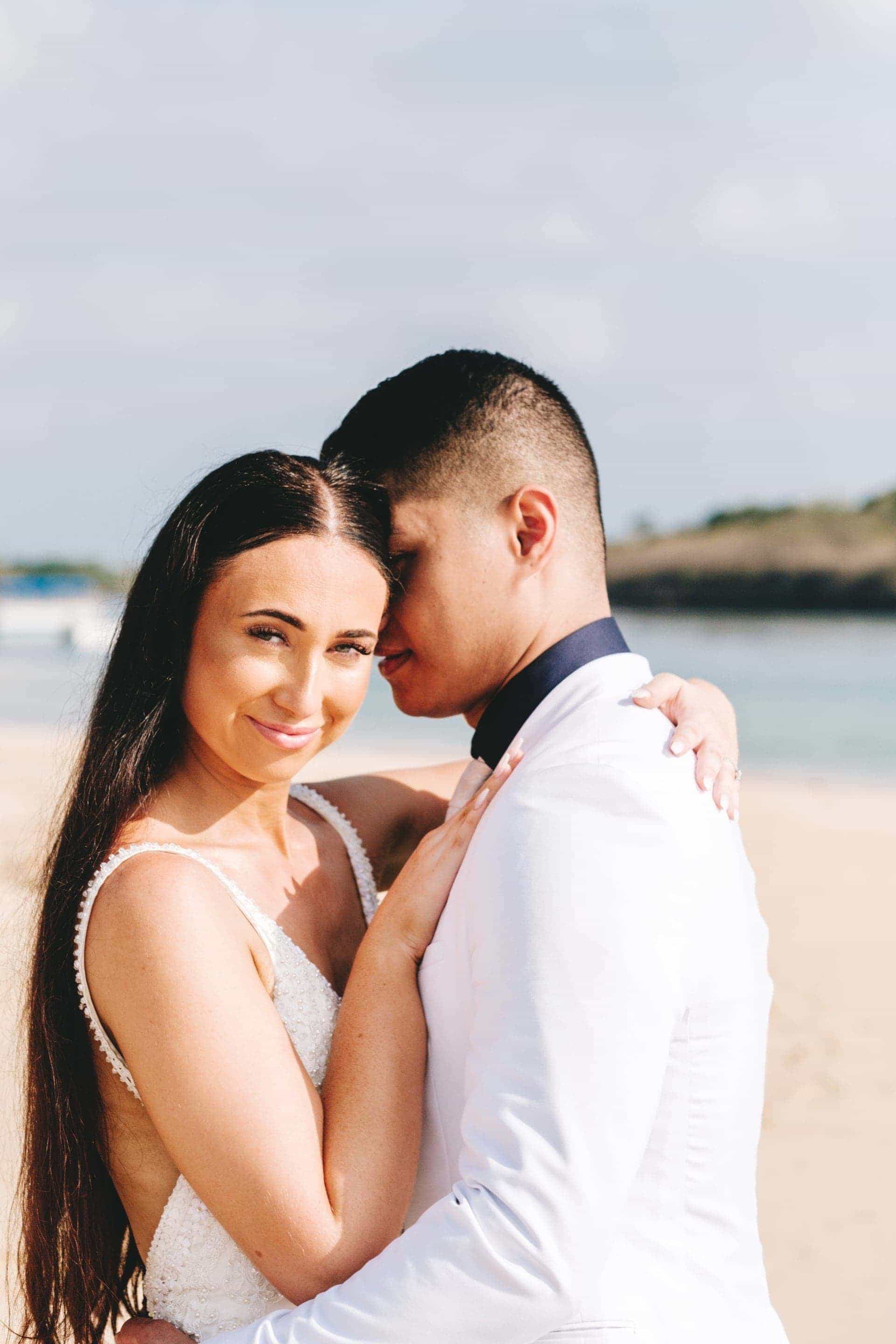 the bride looking at the camera as the groom whispers sweet nothings into her ear.