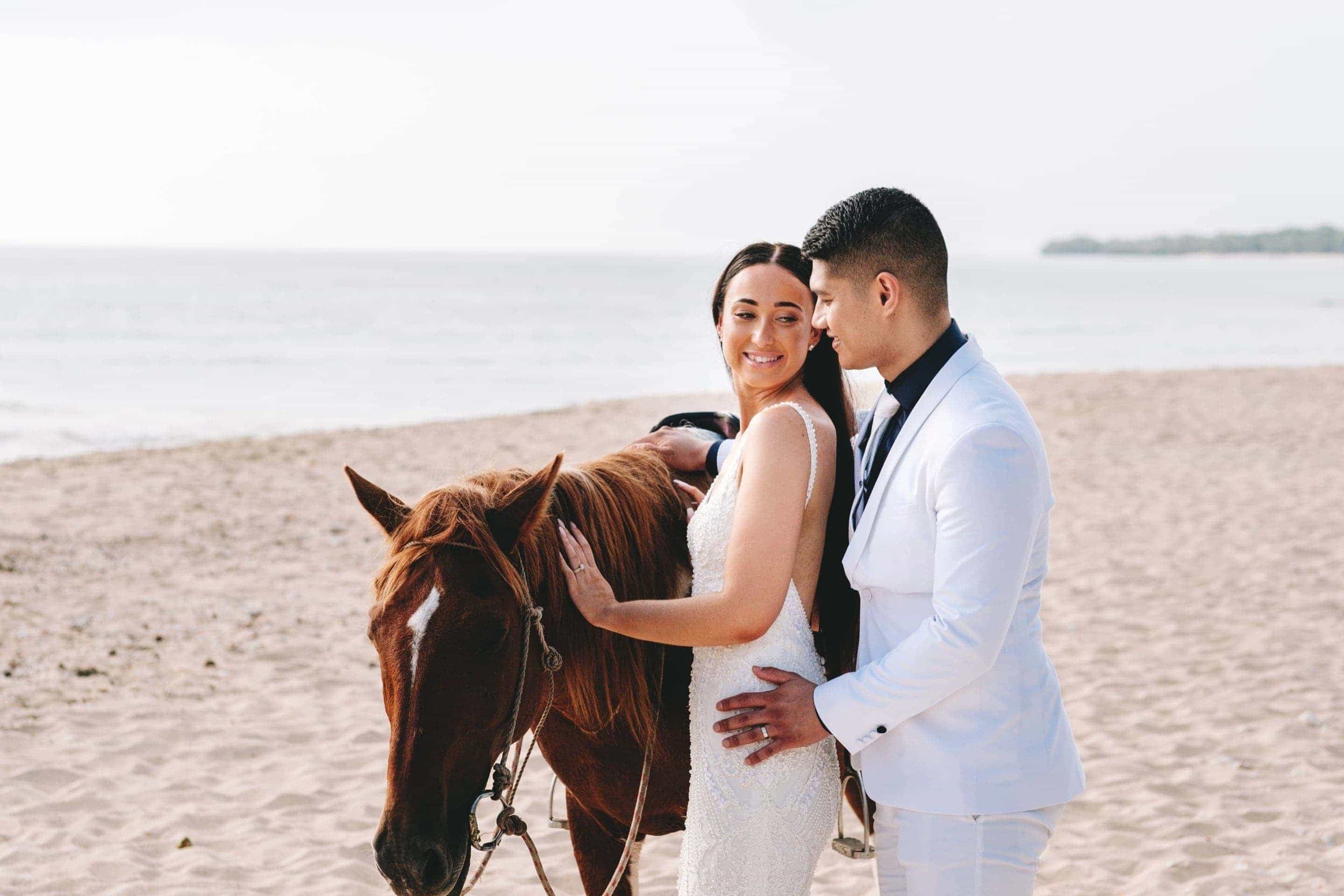 the groom caresses the bride as they pet a local horse