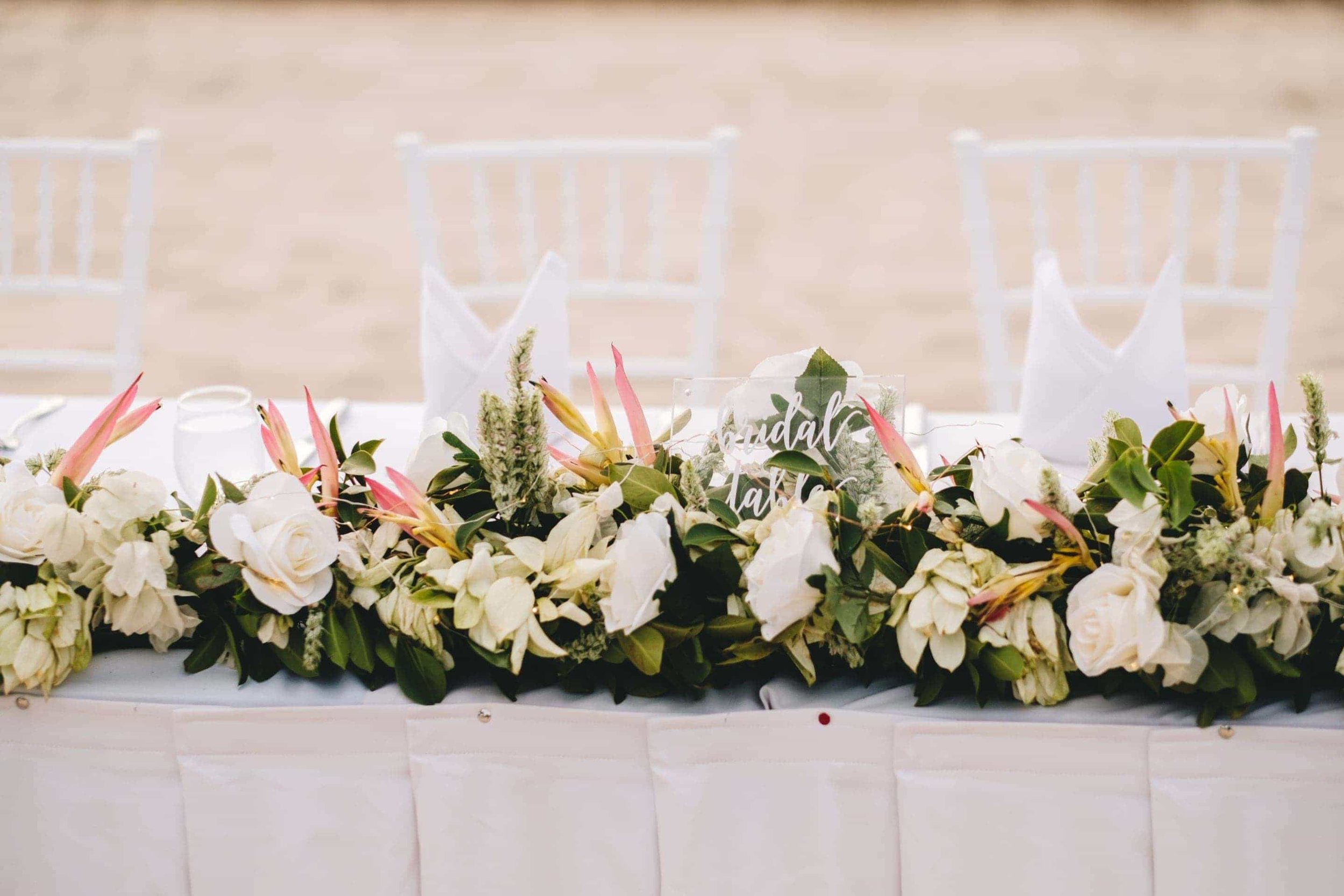 the bridal table covered in white tropical flowers.