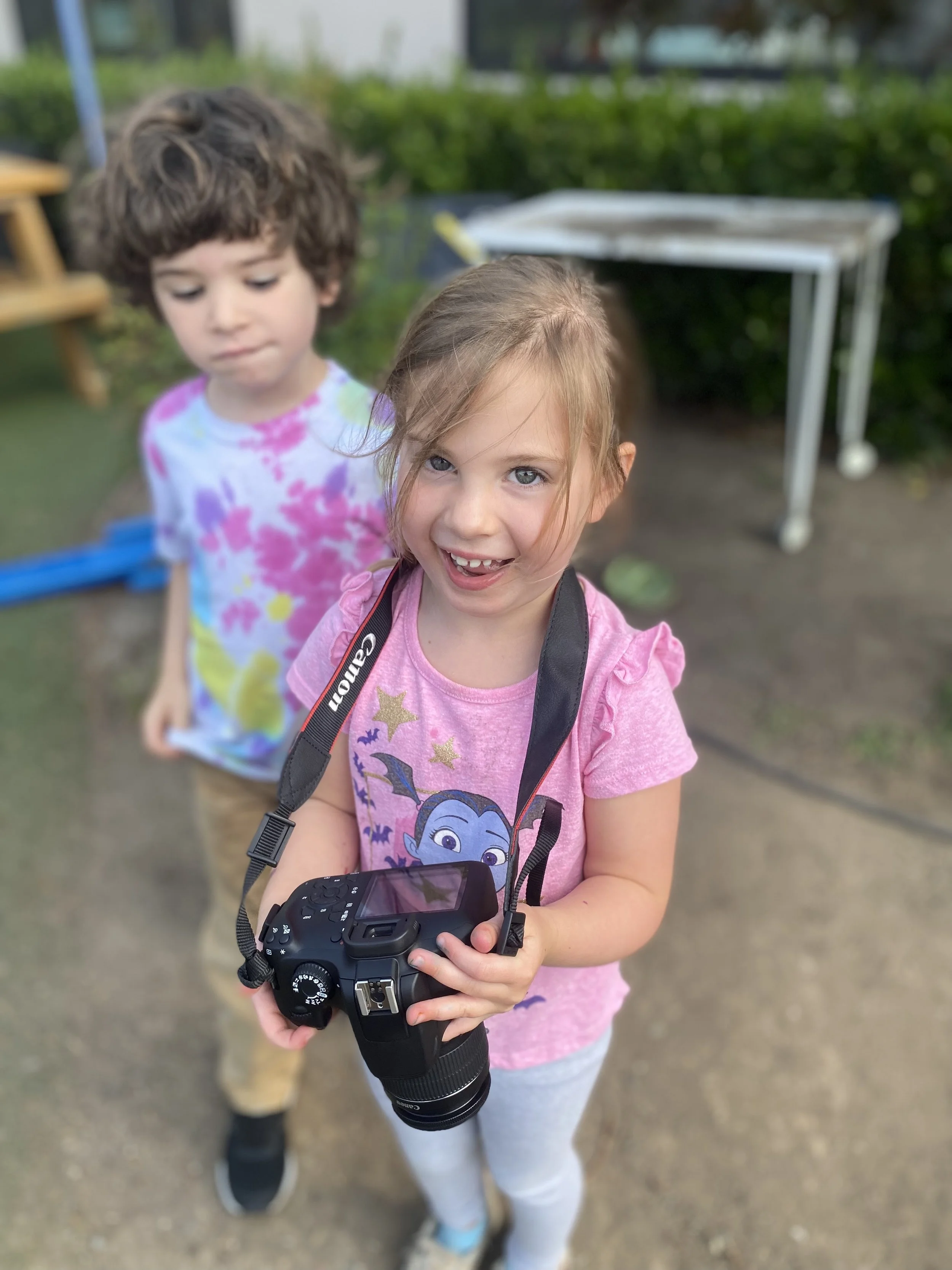 Smiling child holding a camera outdoors