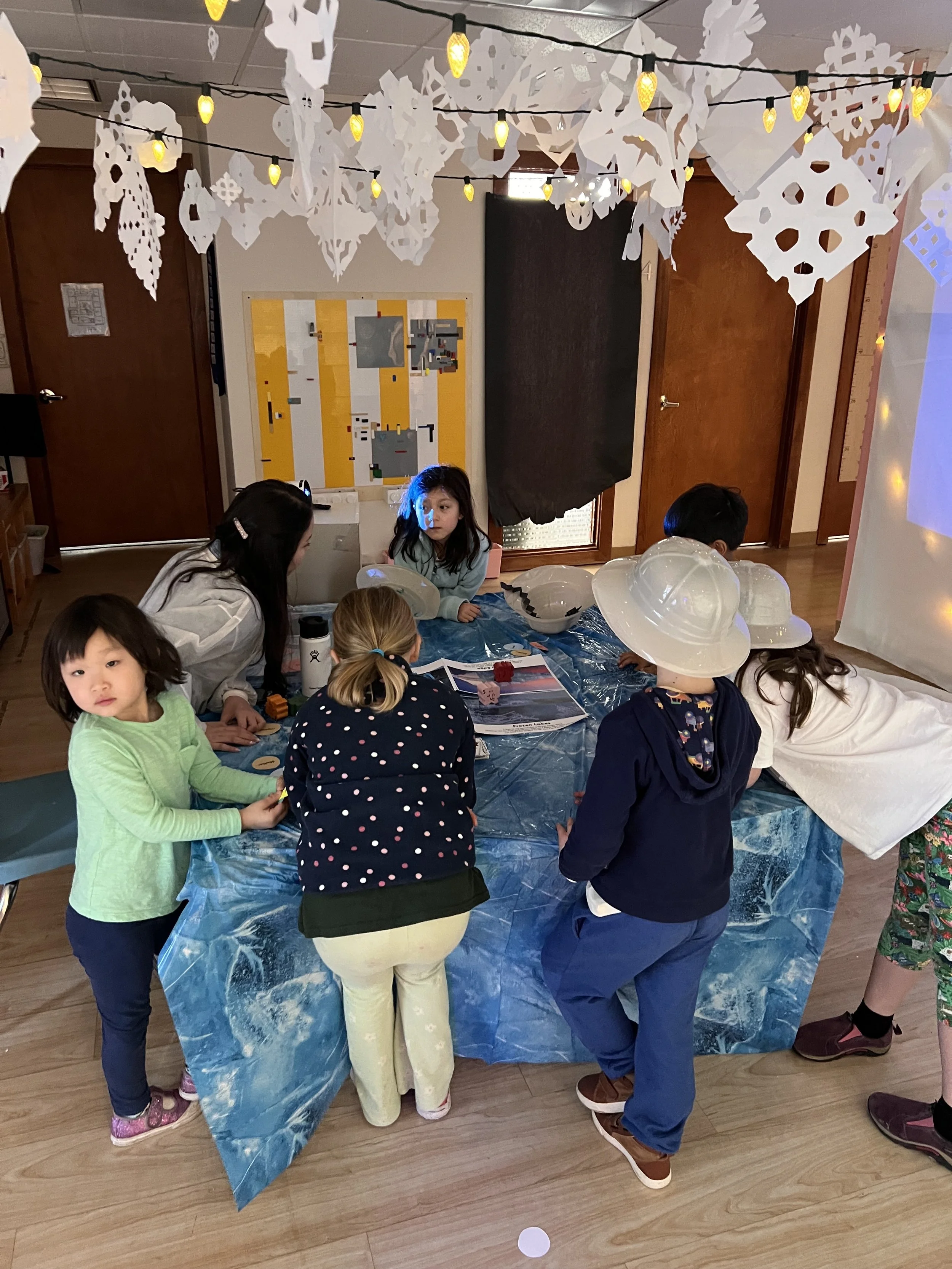 Students gathered around a table working on a hands-on classroom project.