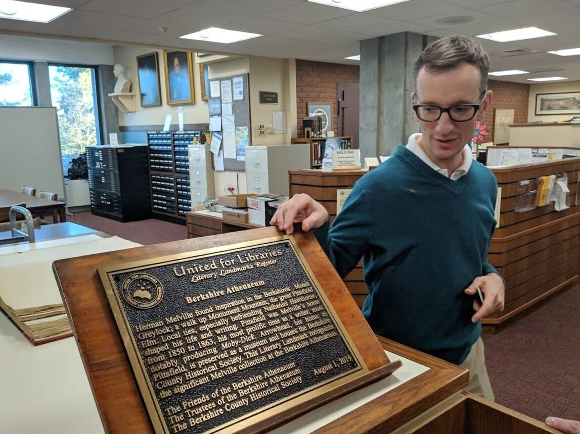 Library Director Alex Raczkowski proudly shows off the library’s literary landmark plaque.