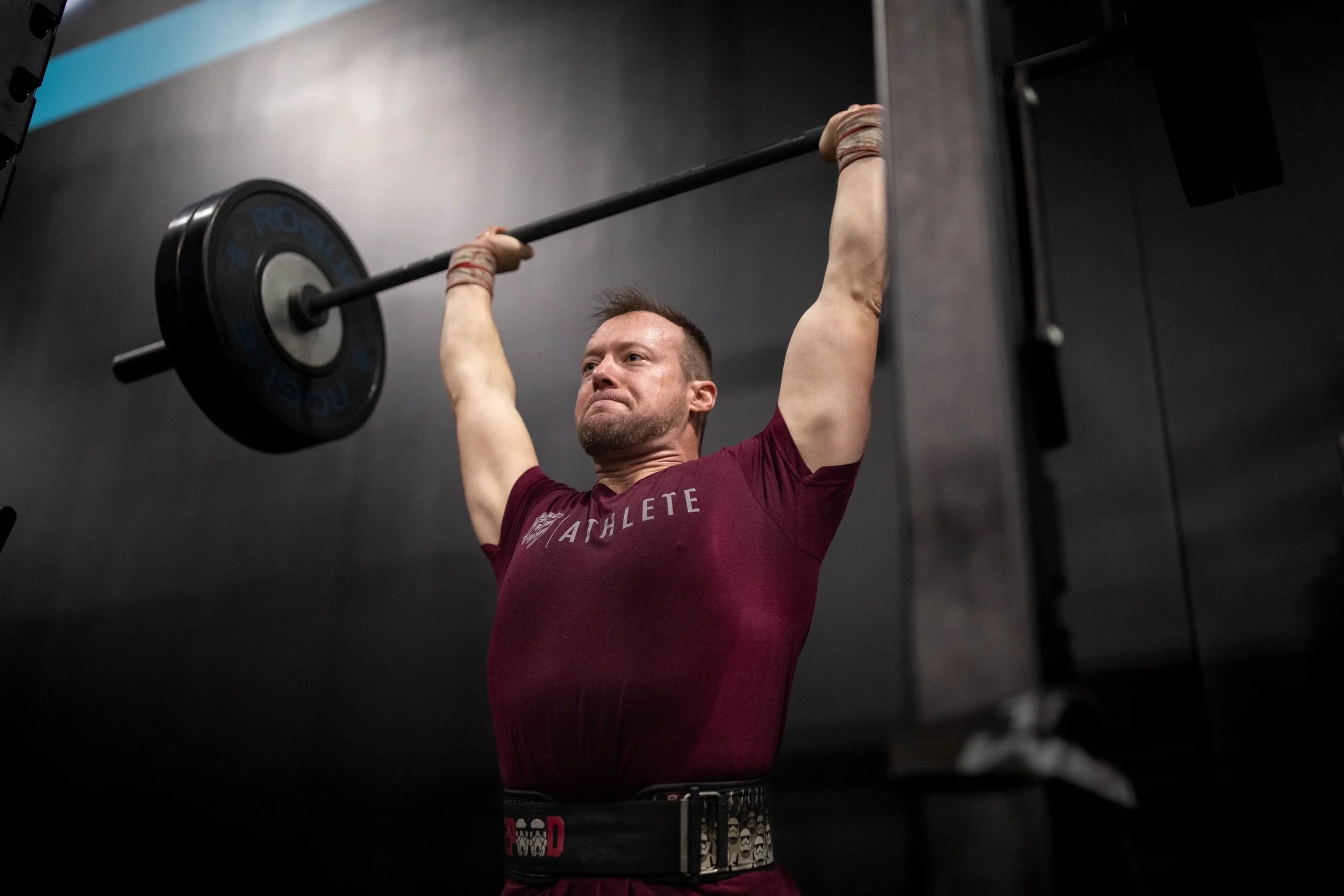Man lifting barbell overhead in a gym.