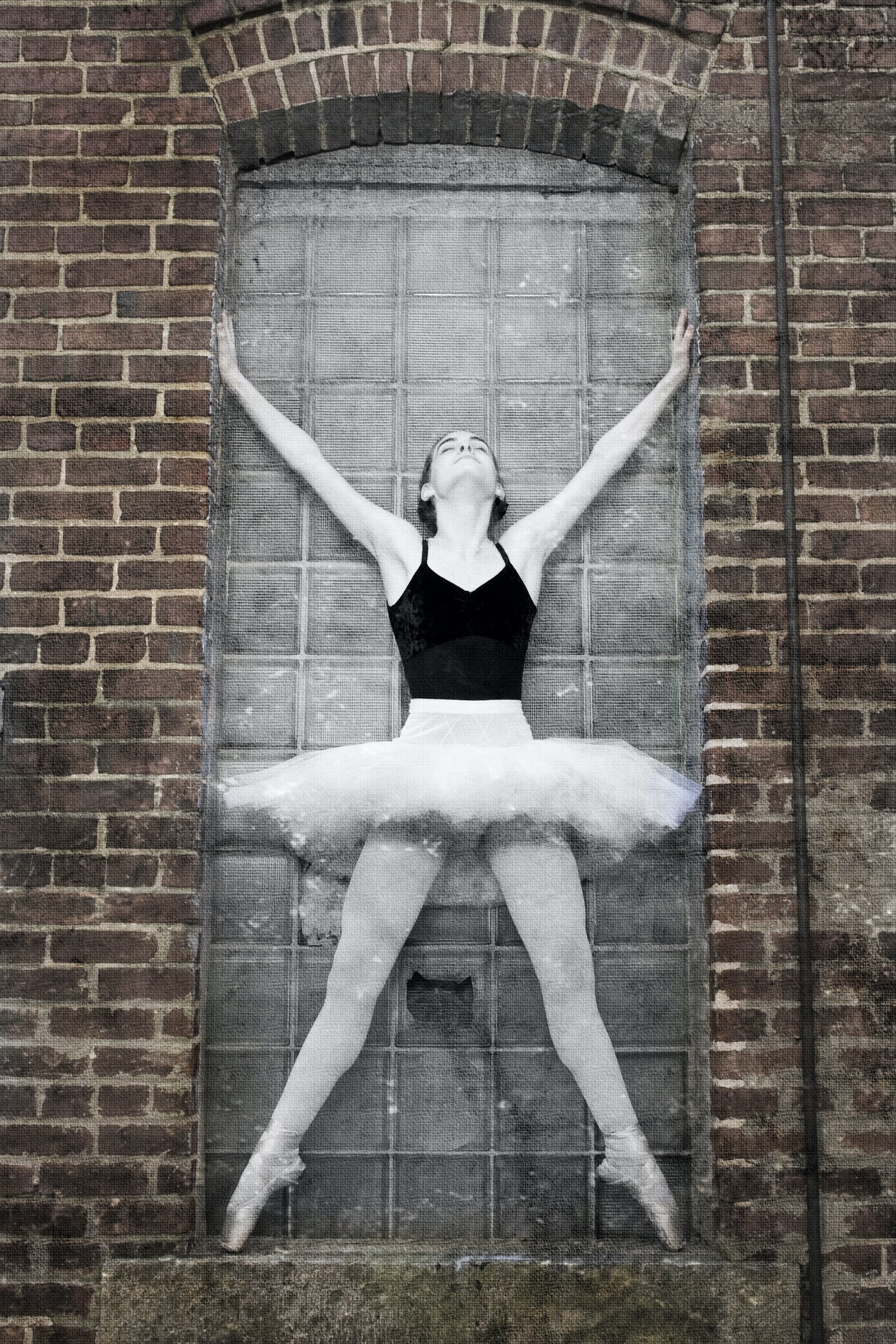 Senior photo ballerina on pointe in urban setting brick wall 