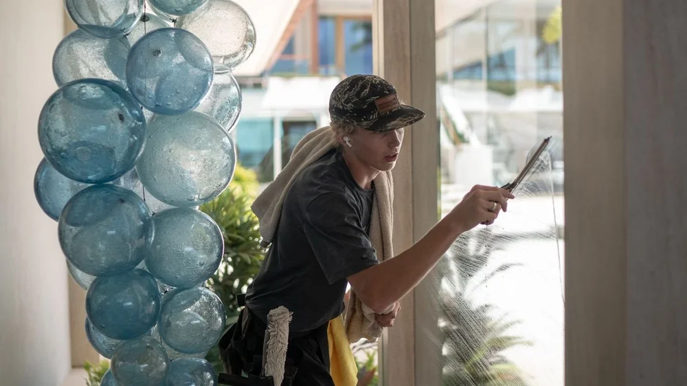 Window cleaner hand squeegeeing a large window at a Kihei home