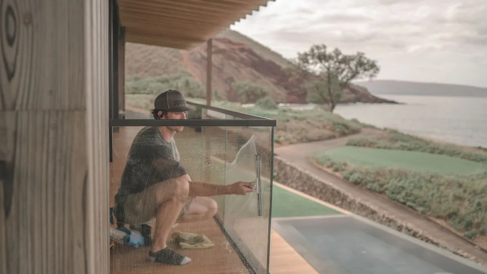 Cleaning a glass lanai railing at an oceanfront Wailea home