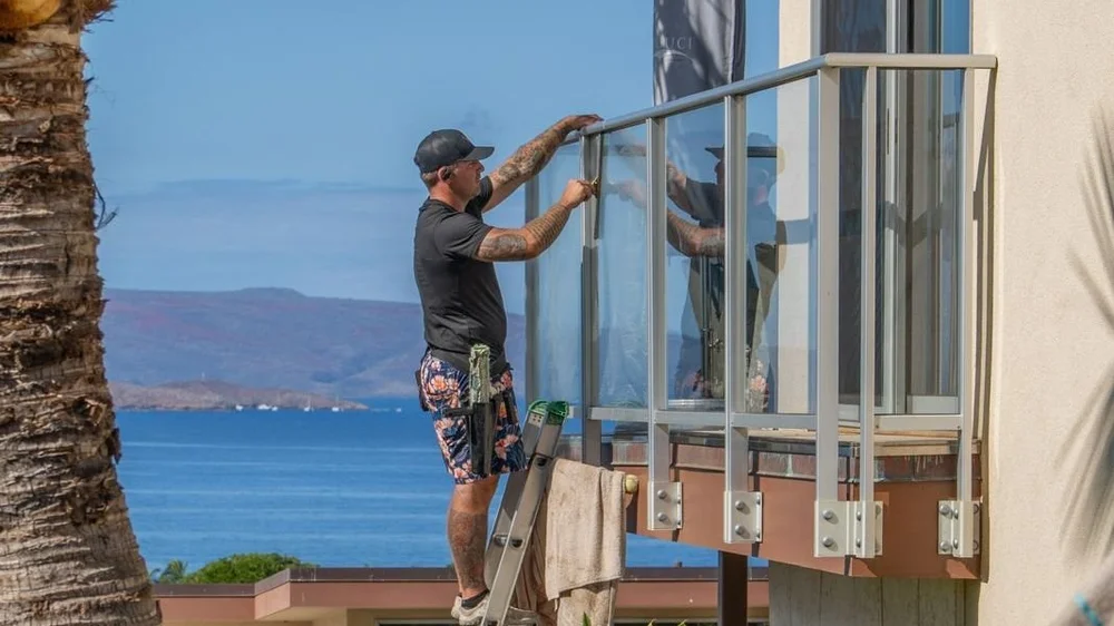 Window cleaner hand cleaning glass balcony railings at a Wailea home with an ocean view