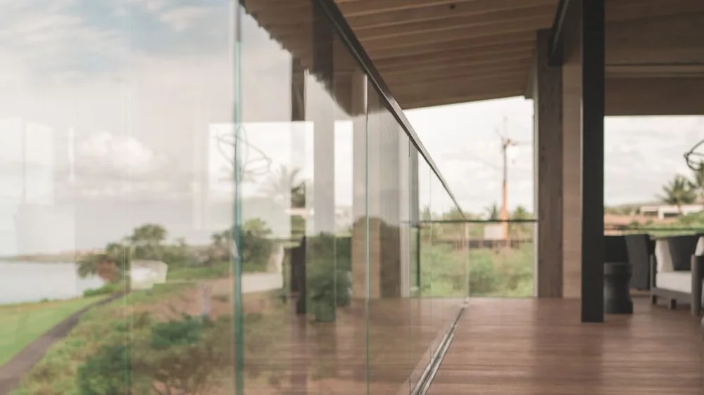 Clean frameless glass railings along a covered lanai at a Maui home