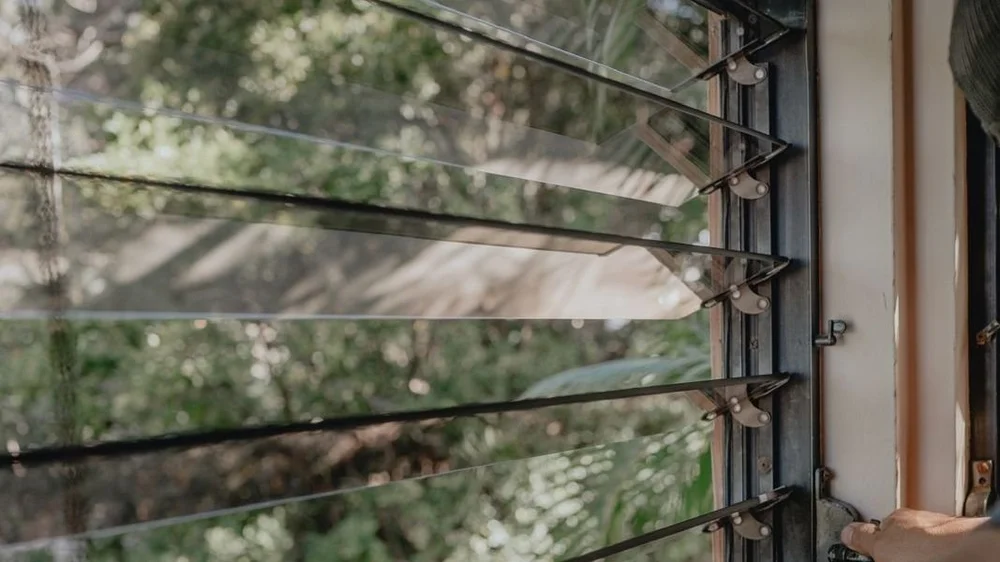 Hand cleaning glass jalousie louver windows in a Maui home