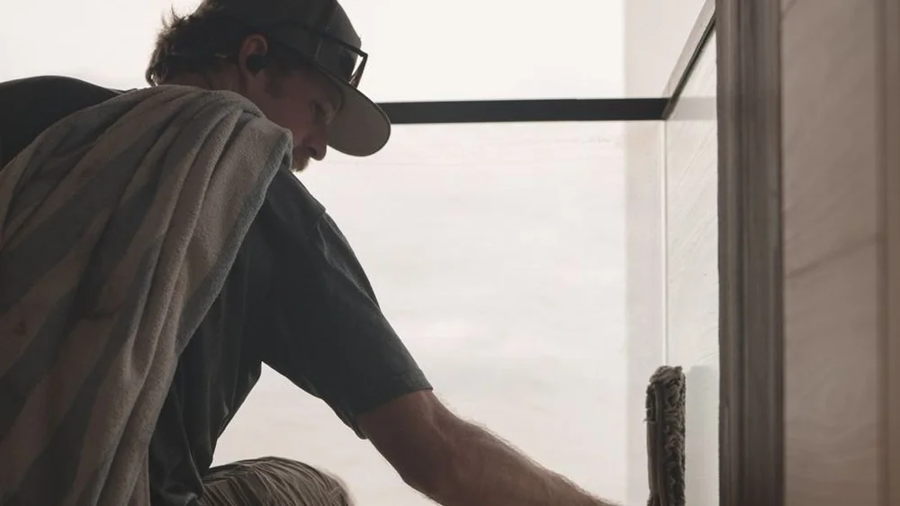 Window cleaner scrubbing a glass panel by hand on a Maui lanai