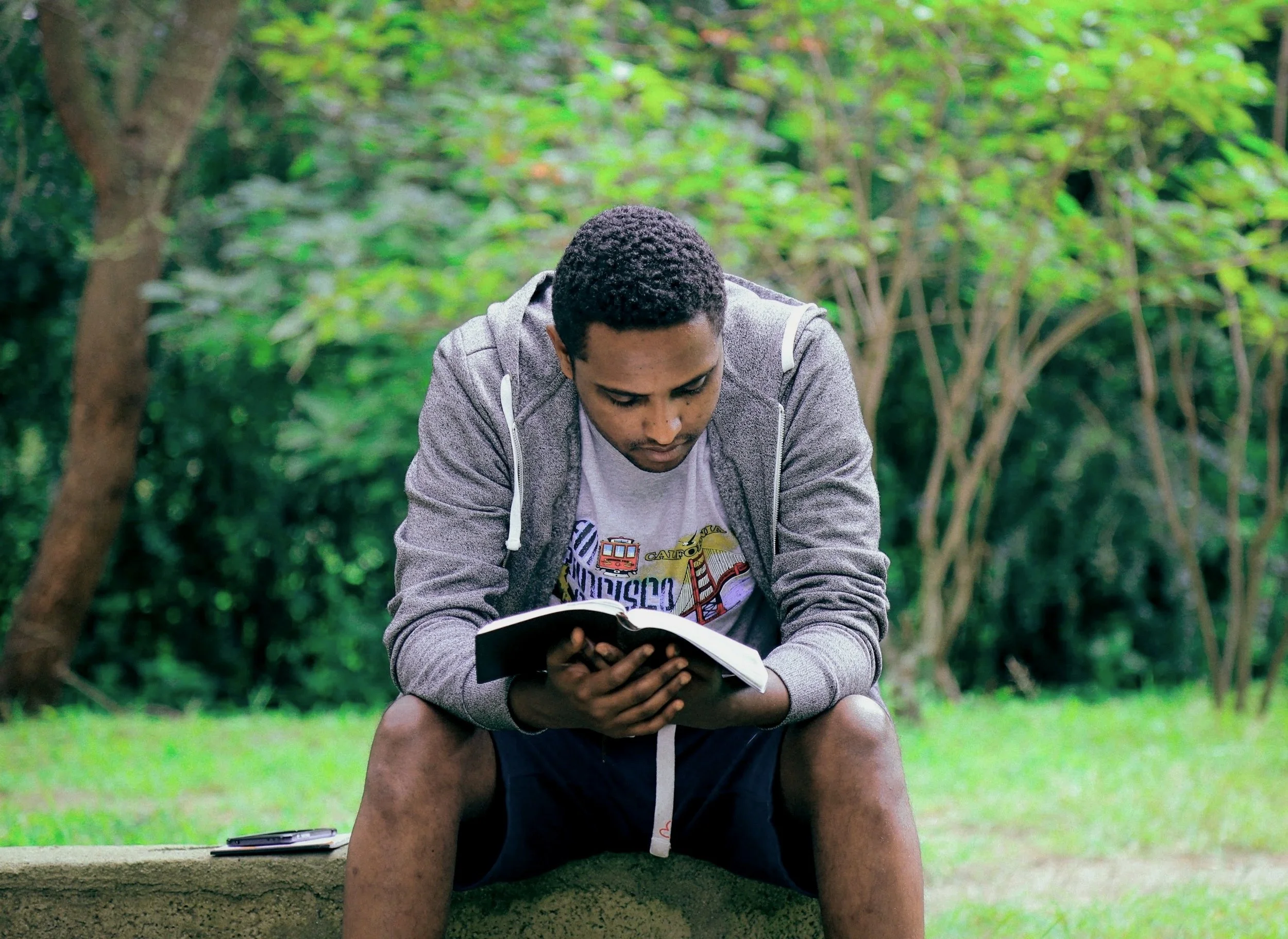 A man sitting in a park reads a book