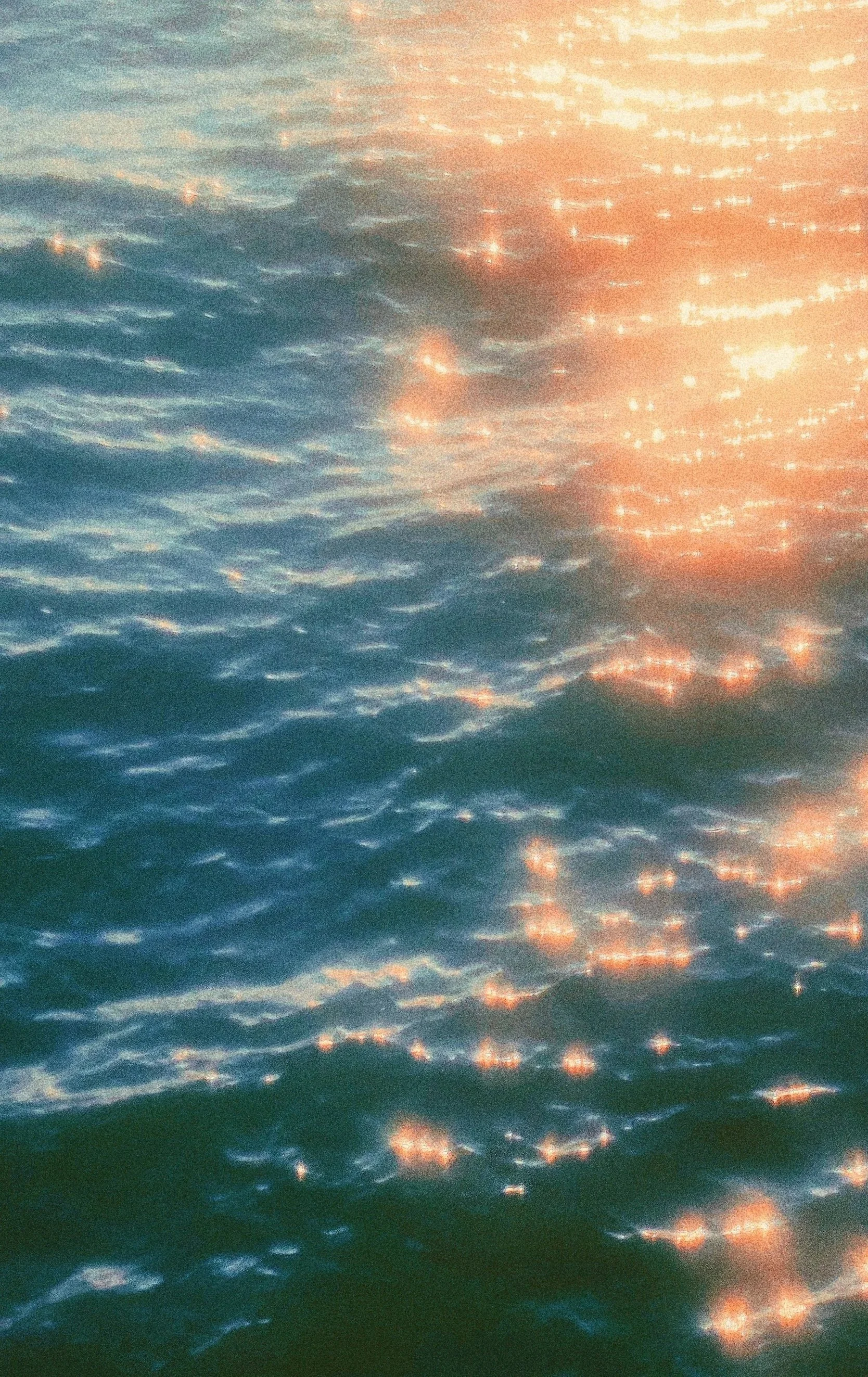 Sunlight reflecting off gentle ocean waves at sunset or sunrise, creating a shimmering effect on the water's surface.